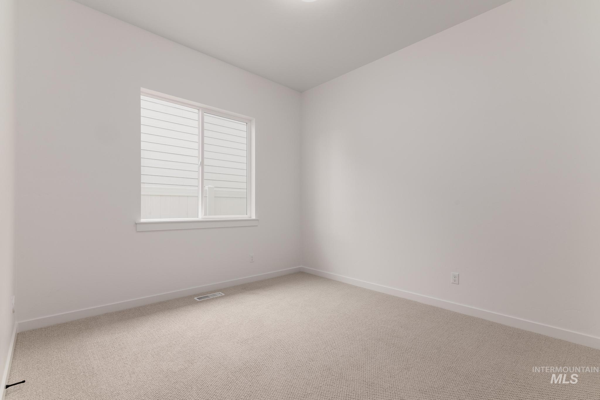 Carpeted spare room featuring baseboards