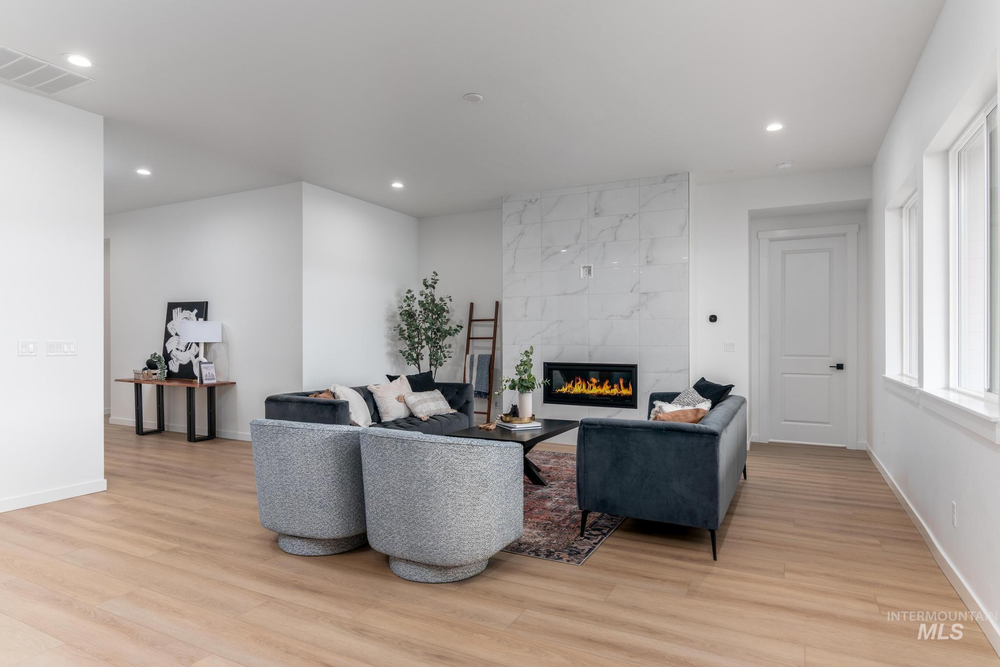 Living area with a tiled fireplace, light wood-type flooring, and recessed lighting