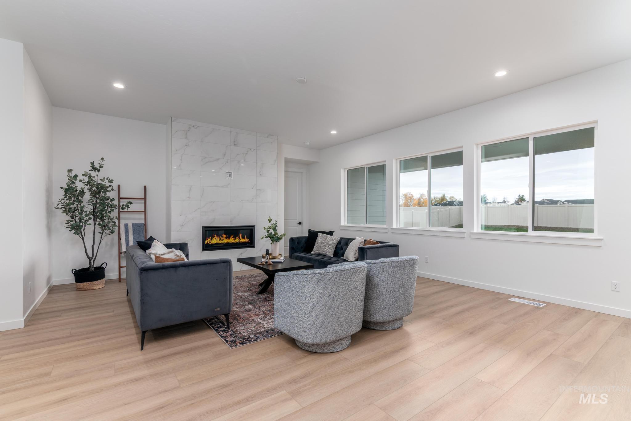 Living area with a fireplace, light wood finished floors, and recessed lighting