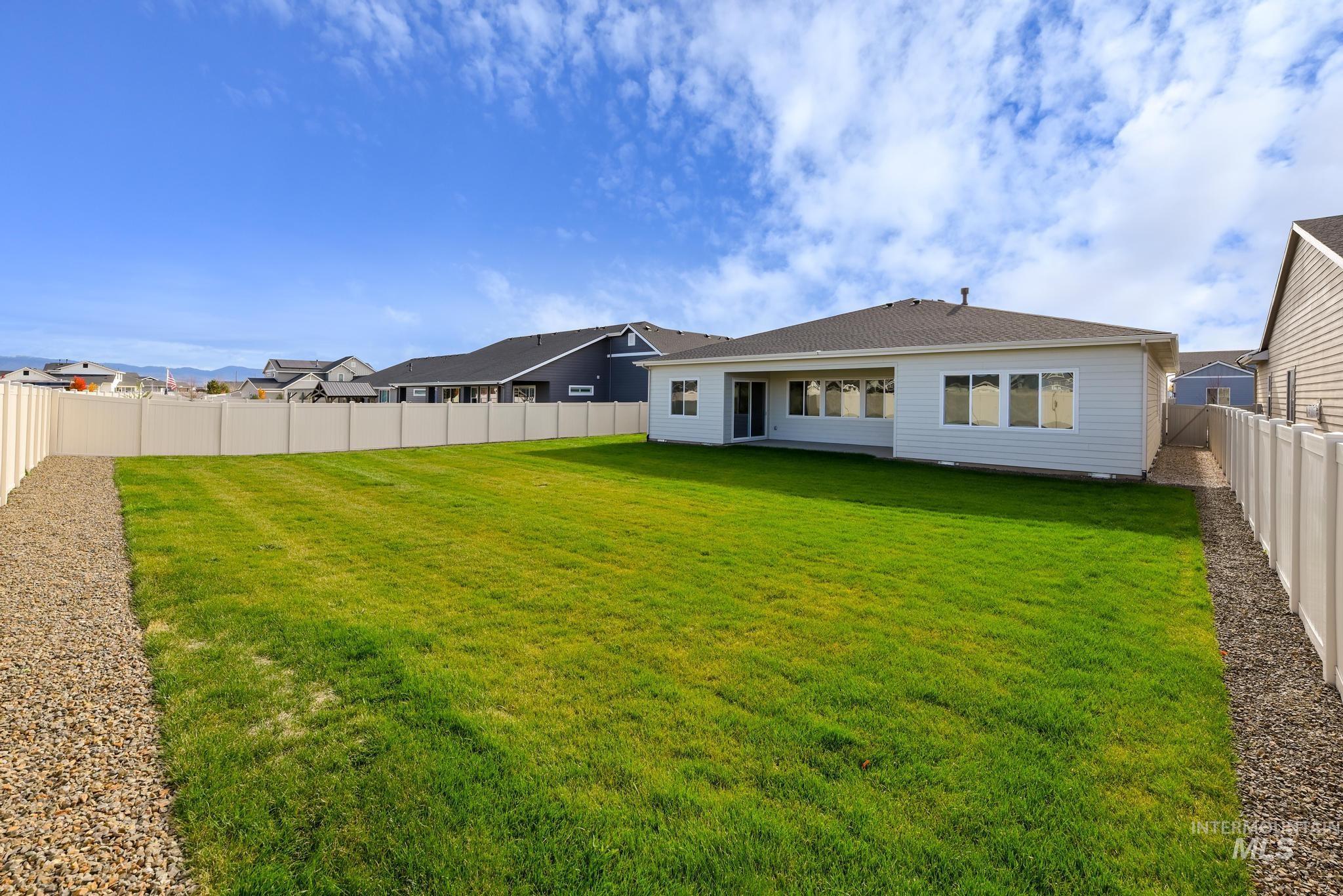Rear view of house with a fenced backyard and a patio area