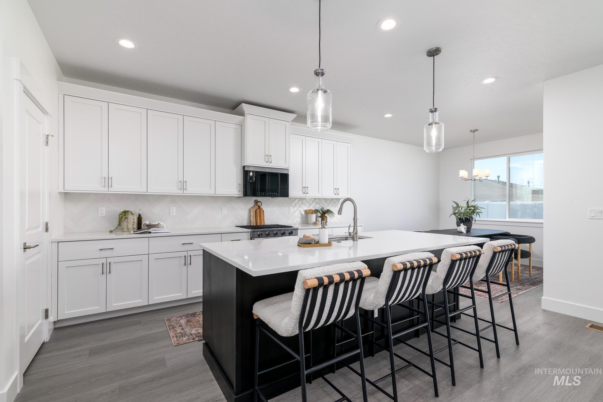 Kitchen with white cabinetry, a kitchen breakfast bar, pendant lighting, recessed lighting, and tasteful backsplash
