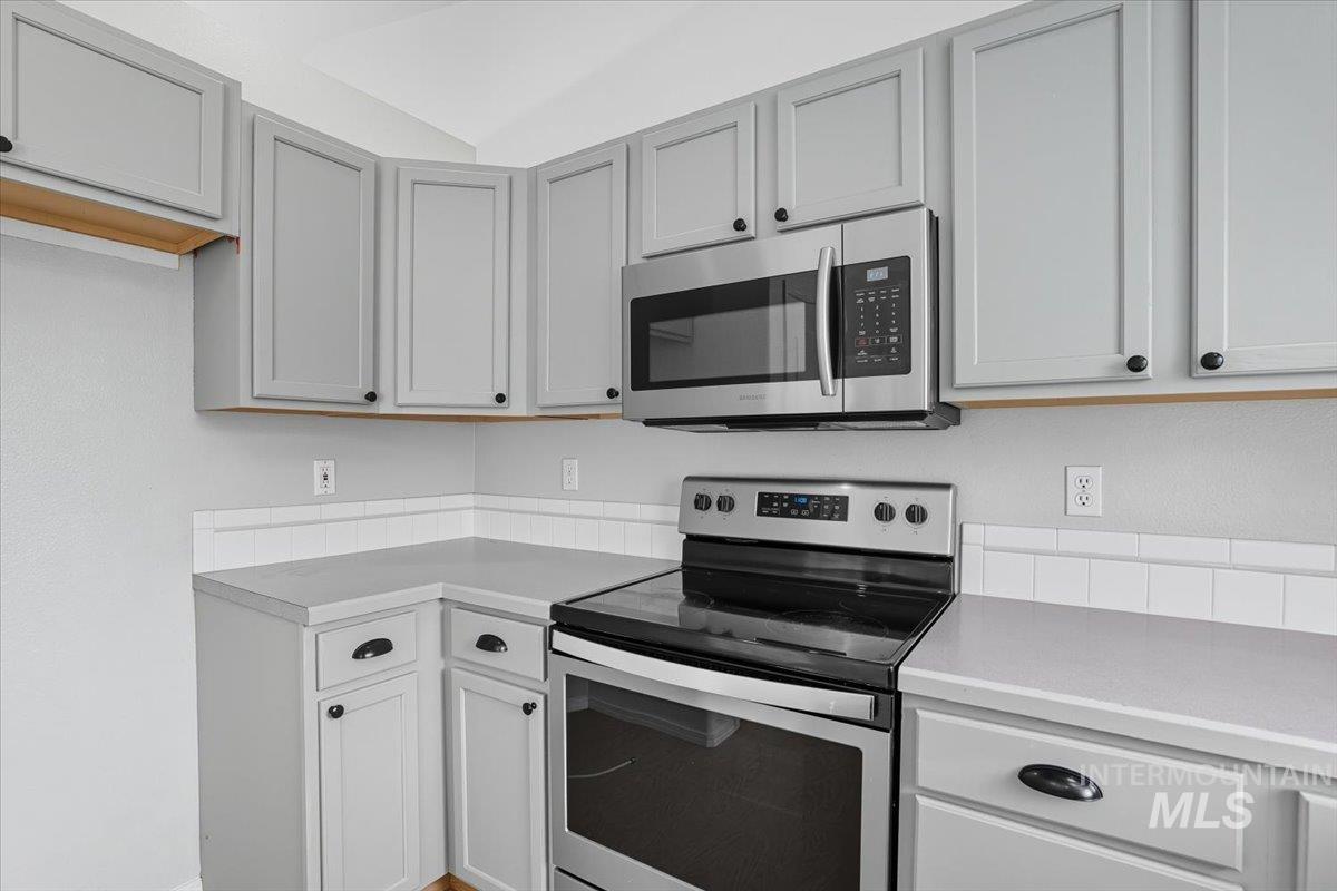 Kitchen featuring appliances with stainless steel finishes, light countertops, and gray cabinets