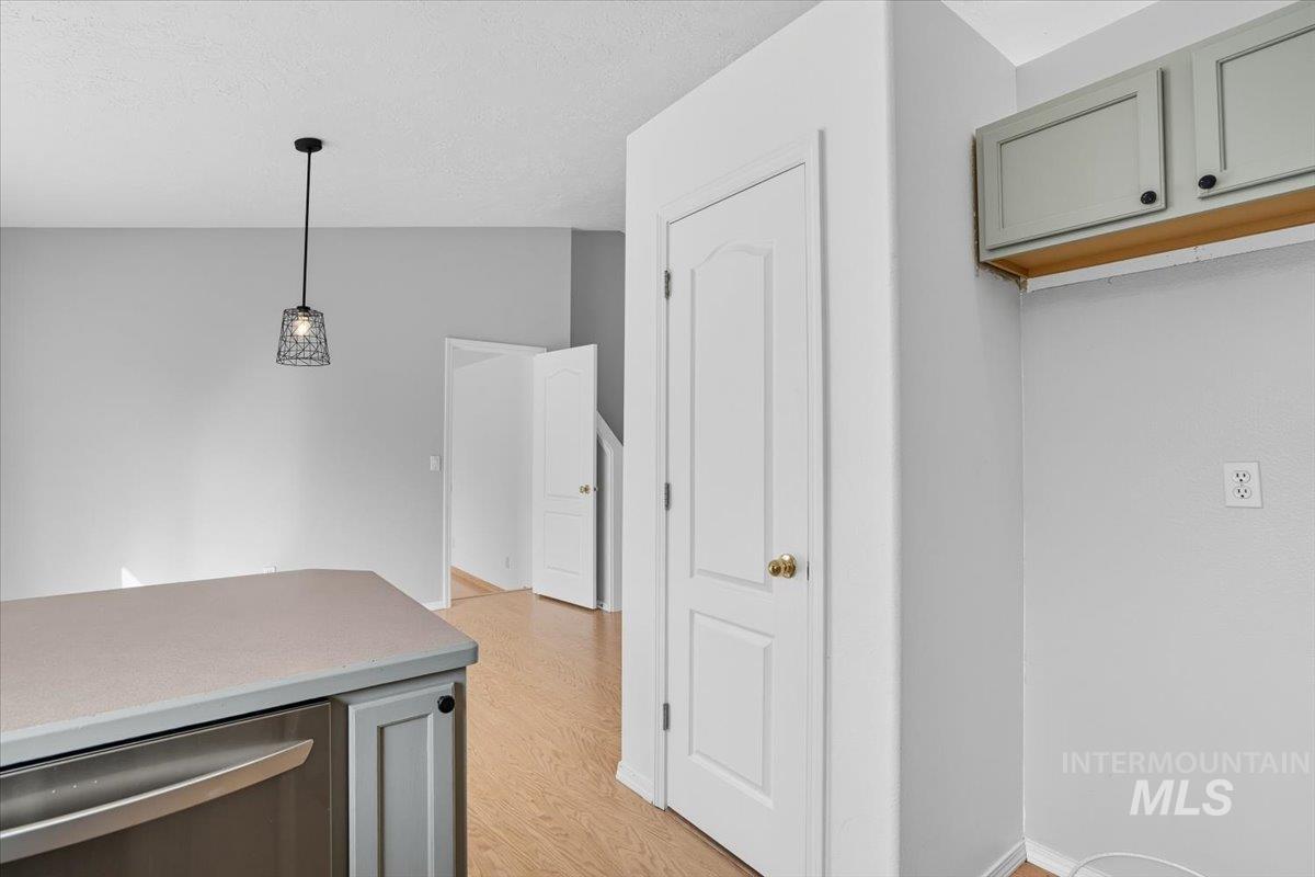 Kitchen featuring gray cabinetry, dishwasher, light countertops, pendant lighting, and a textured ceiling