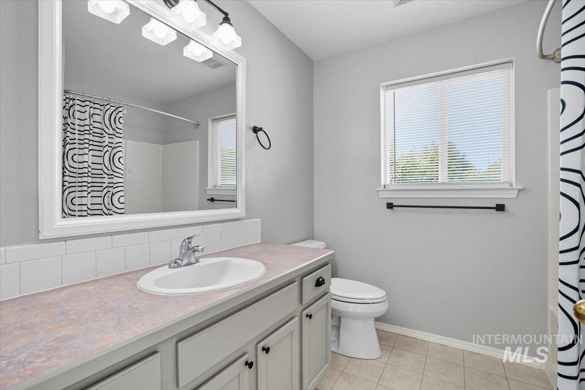 Bathroom with vanity, light tile patterned floors, a shower with curtain, and decorative backsplash