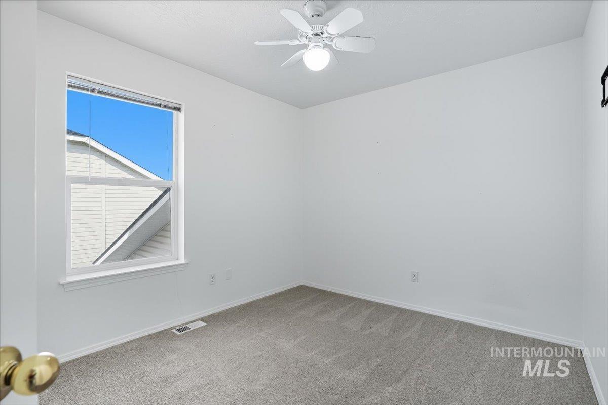 Spare room featuring light carpet and a ceiling fan