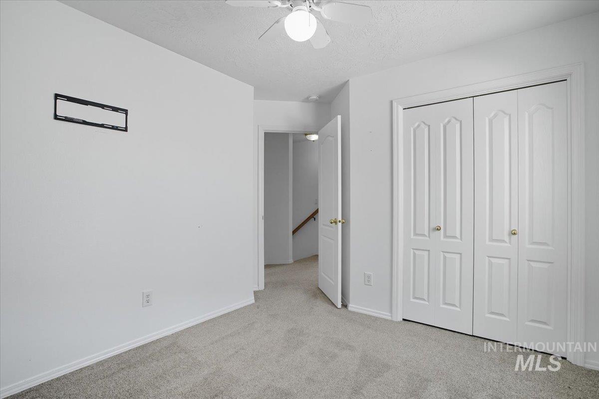 Unfurnished bedroom with carpet, a textured ceiling, ceiling fan, and a closet
