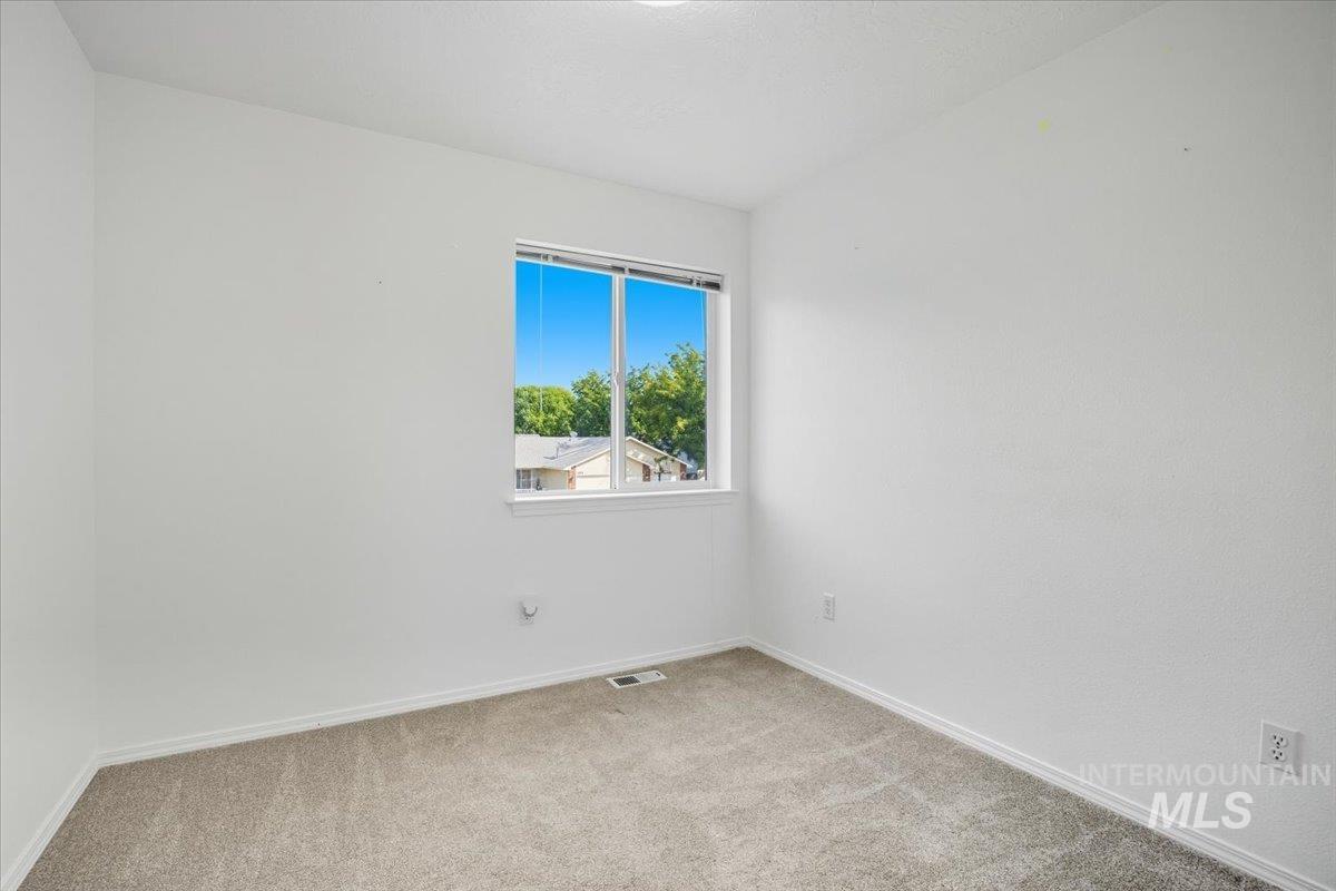 Spare room featuring light carpet and baseboards