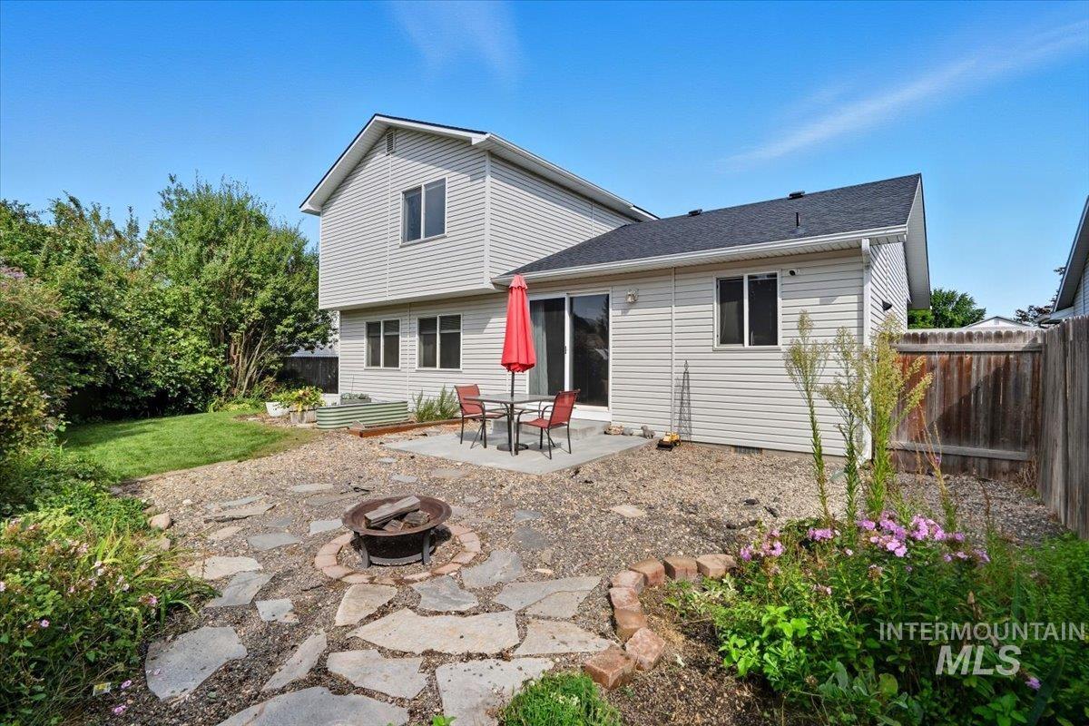 Back of house featuring a patio, an outdoor fire pit, a fenced backyard, and roof with shingles