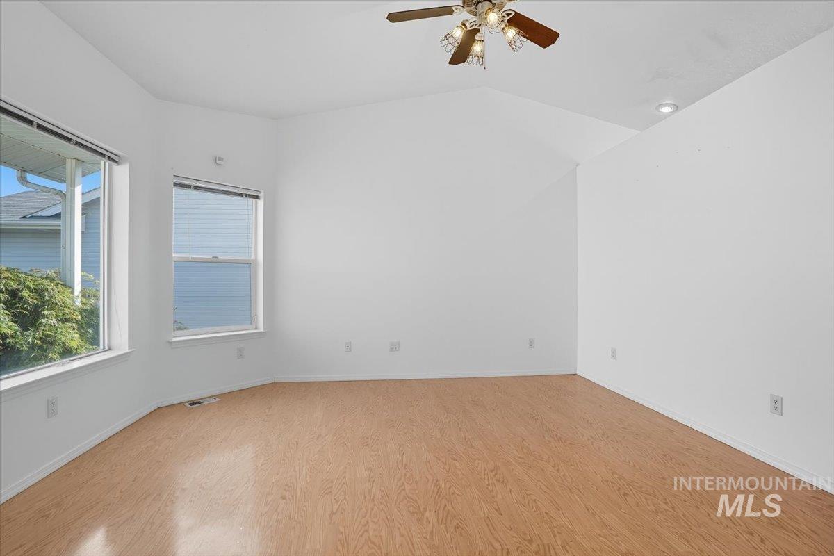 Spare room with light wood-type flooring, lofted ceiling, and ceiling fan