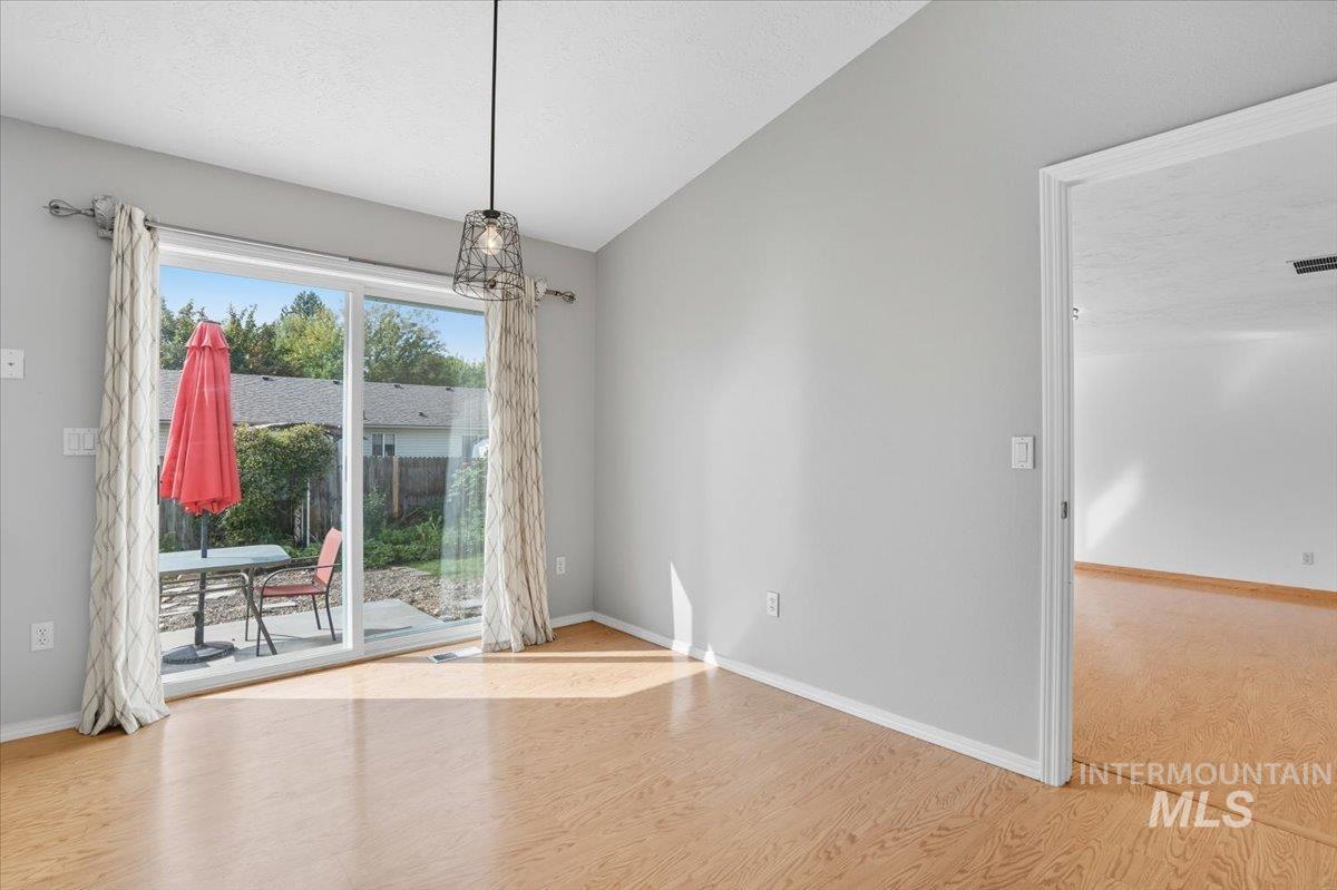 Unfurnished dining area with wood finished floors, a textured ceiling, and lofted ceiling