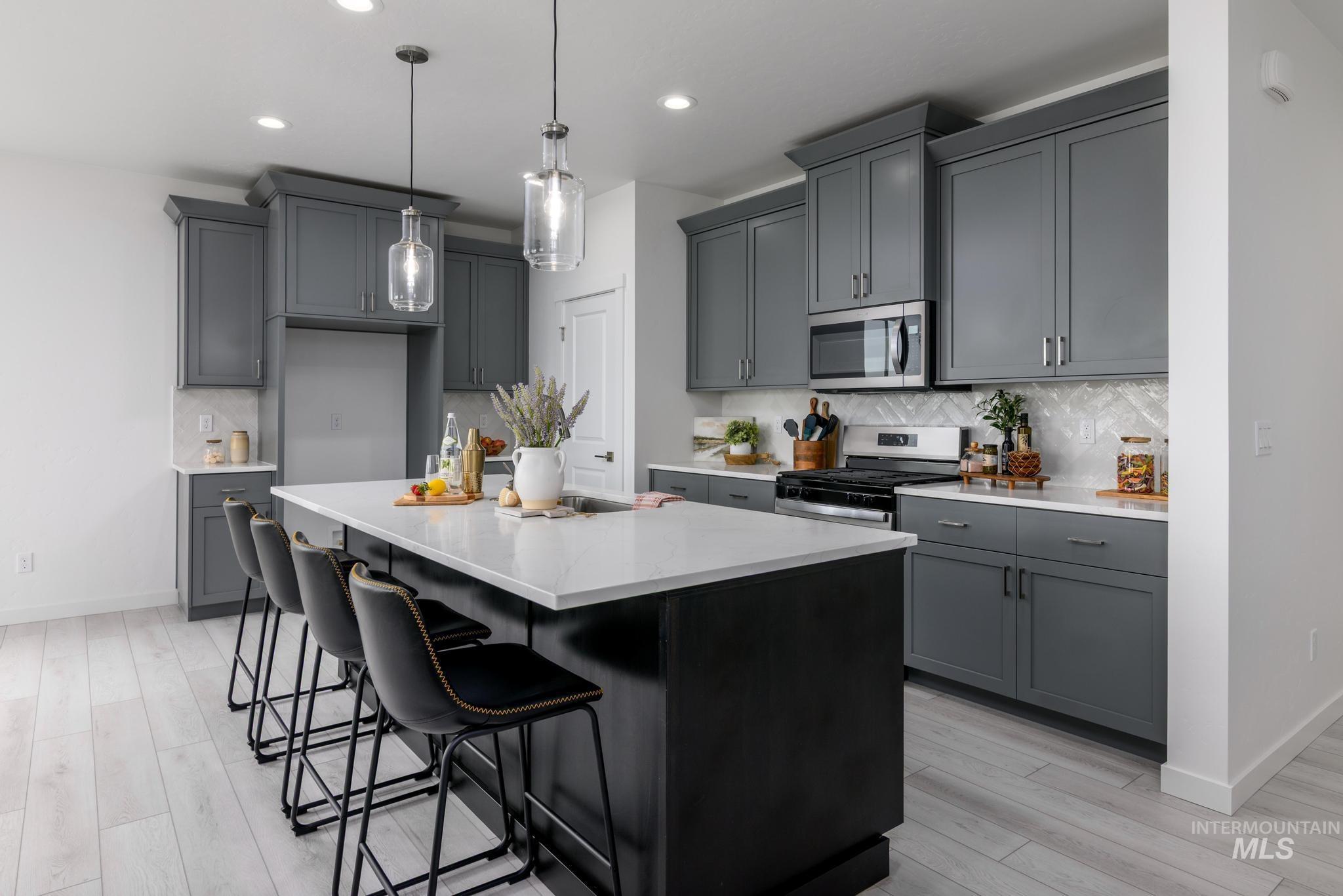 Kitchen with decorative backsplash, a kitchen bar, pendant lighting, stainless steel appliances, and light stone countertops