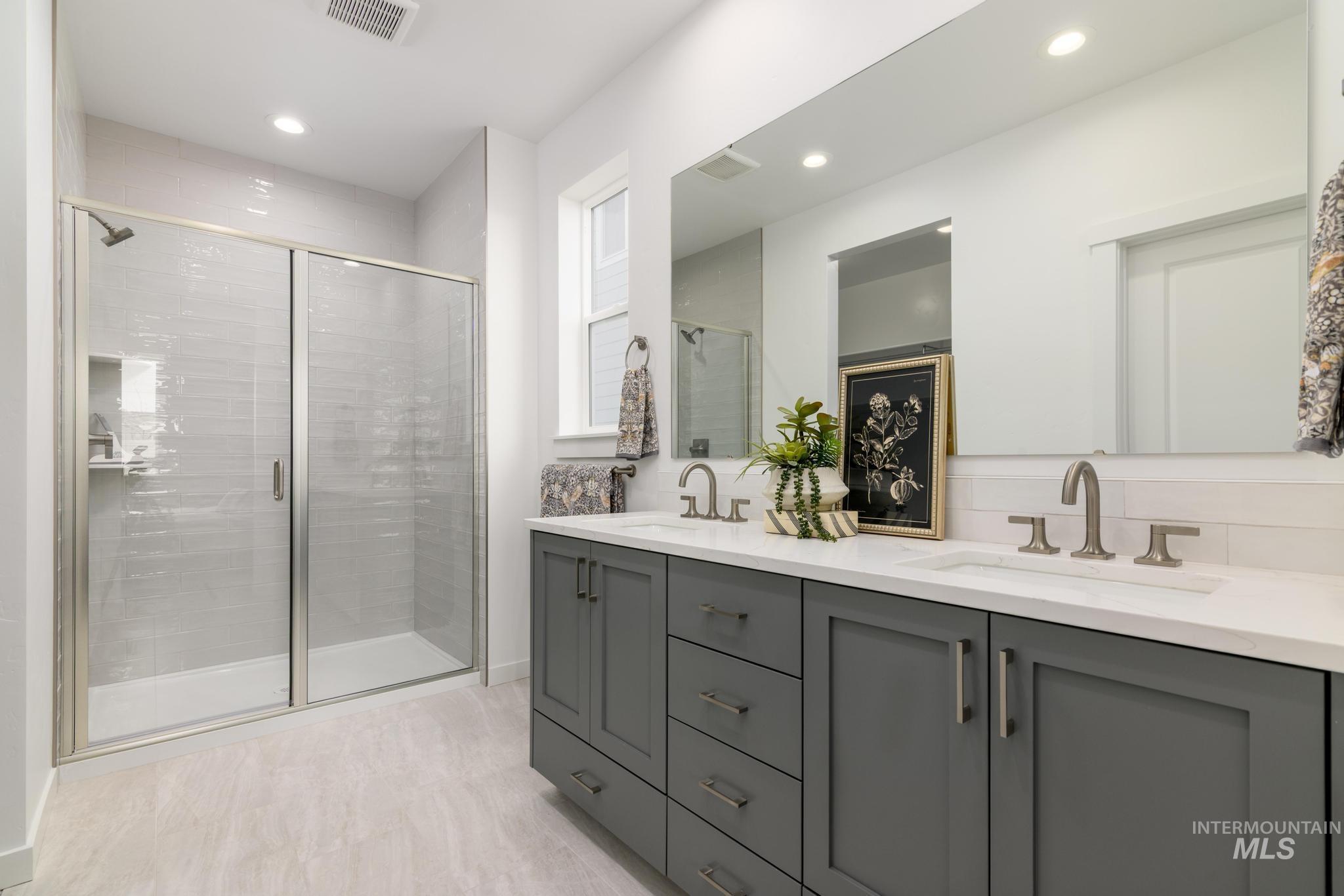 Bathroom featuring double vanity, a stall shower, and recessed lighting