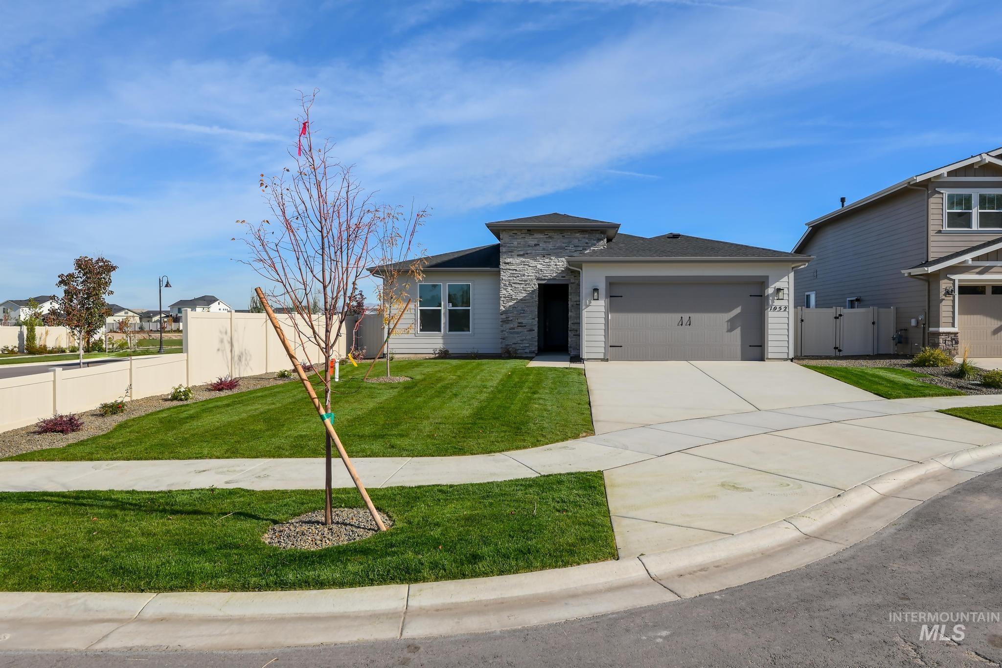 View of front of property featuring concrete driveway, a garage, stone siding, and a gate