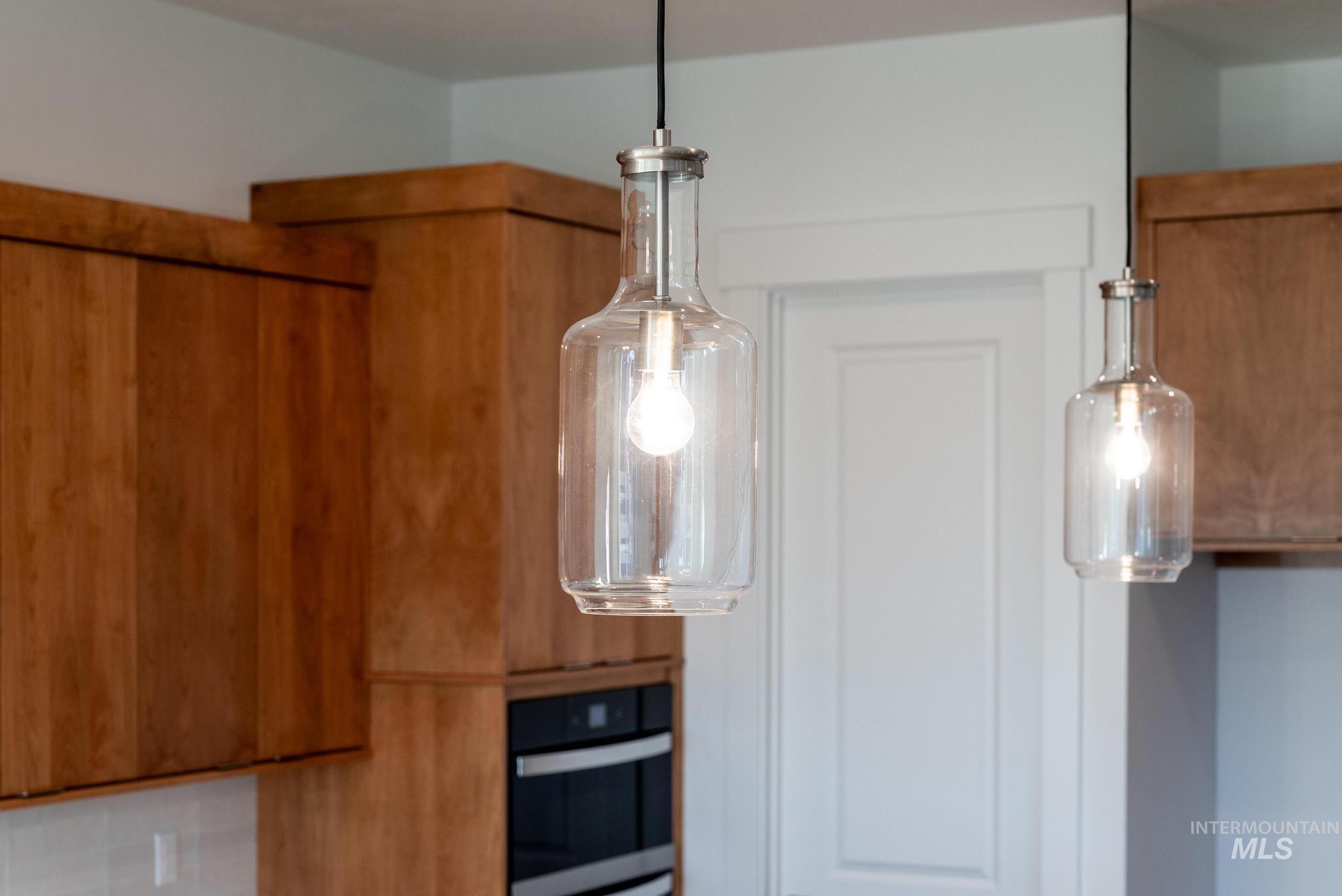 Kitchen view of brown cabinetry, hanging light fixtures, and stainless steel oven