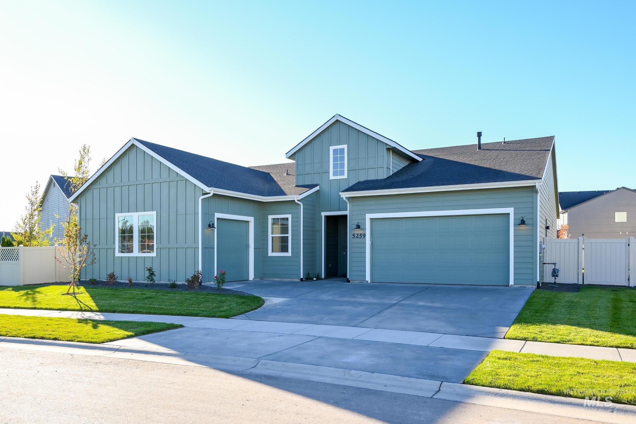 View of front of home with board and batten siding, driveway, a garage, a gate, and roof with shingles