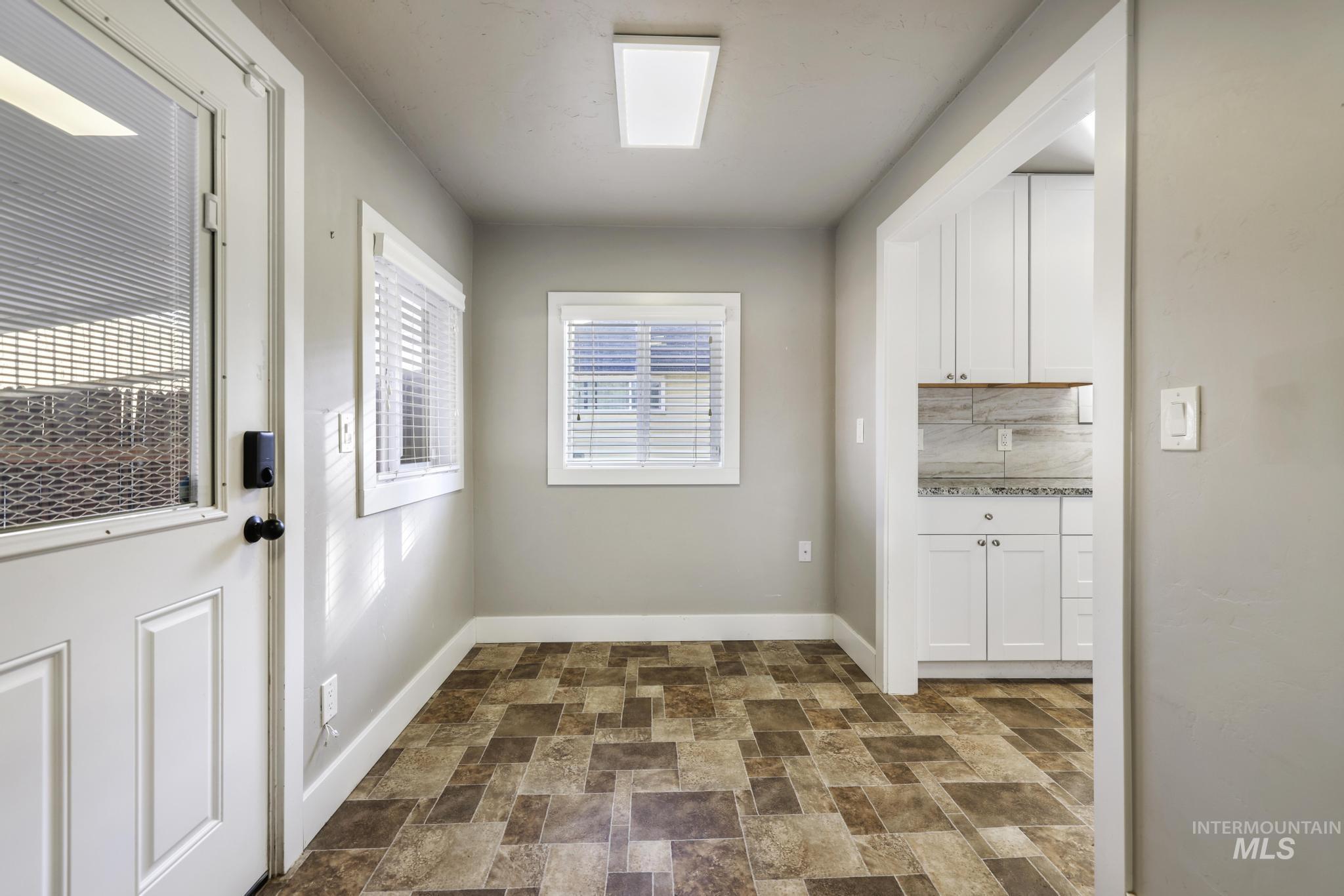 Doorway featuring stone finish floors and baseboards