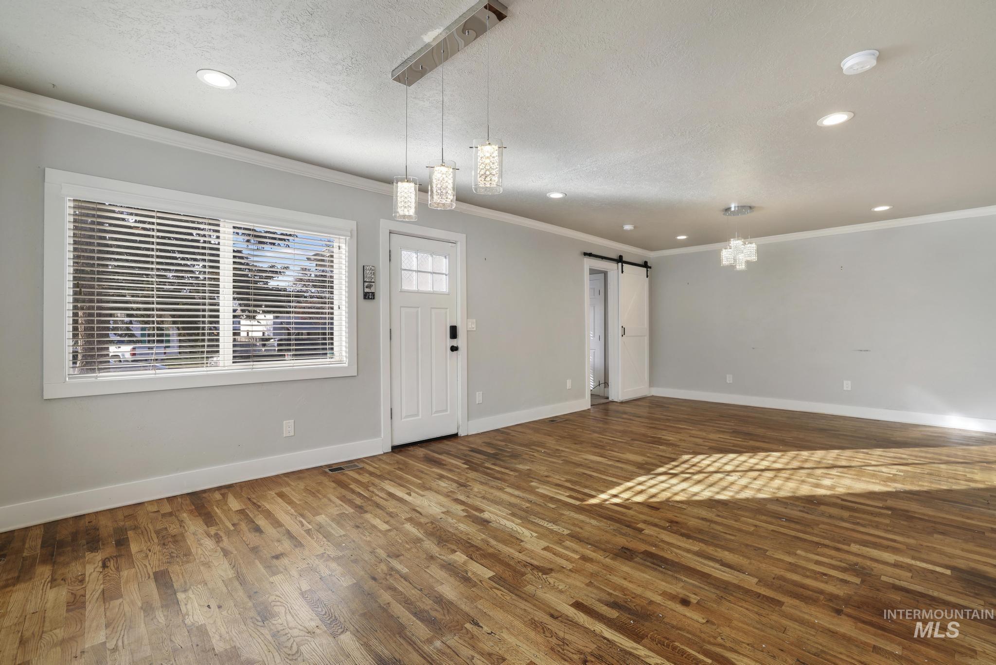 Foyer featuring a barn door, hardwood / wood-style floors, ornamental molding, recessed lighting, and a textured ceiling
