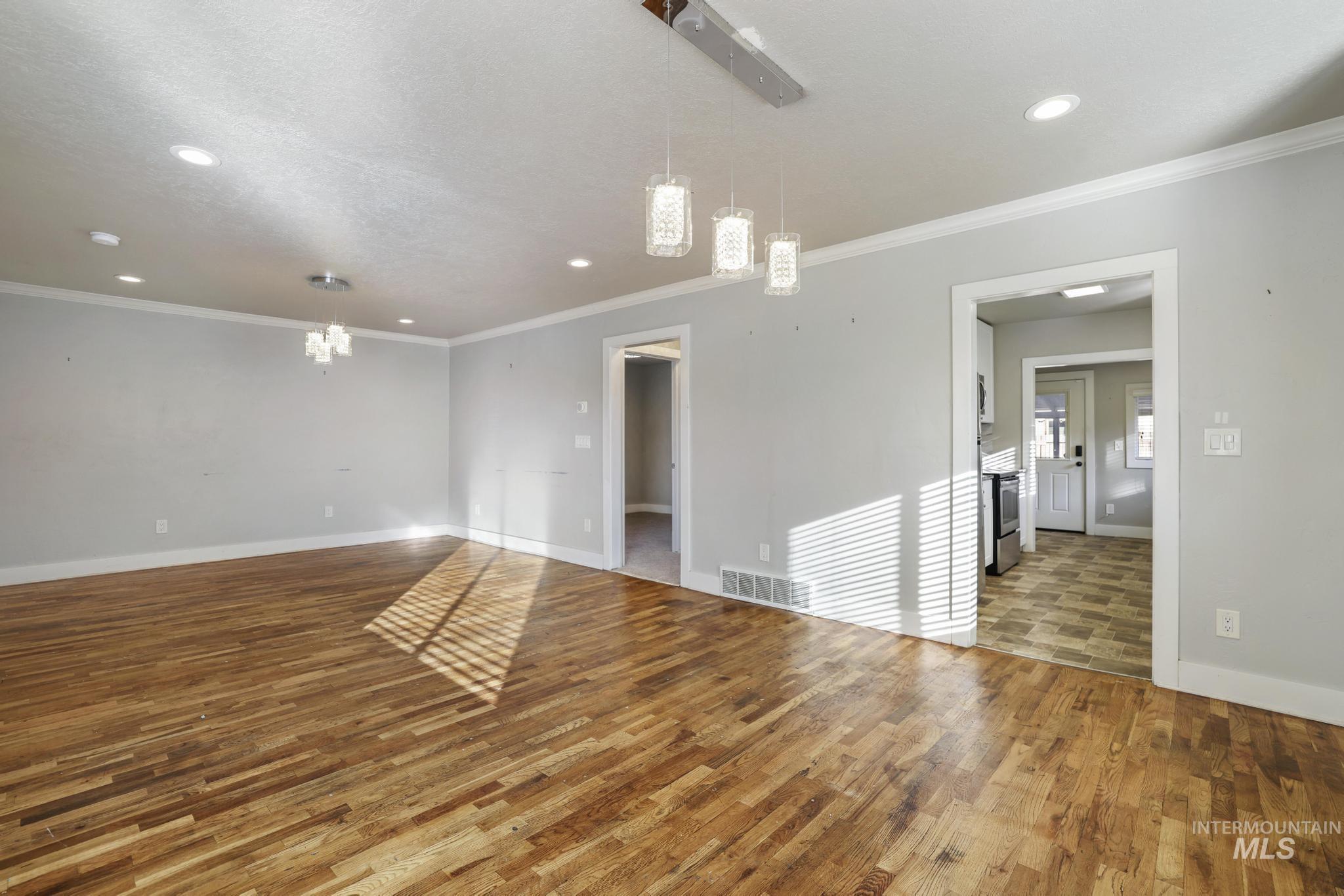 Empty room with hardwood / wood-style flooring, a chandelier, recessed lighting, and crown molding