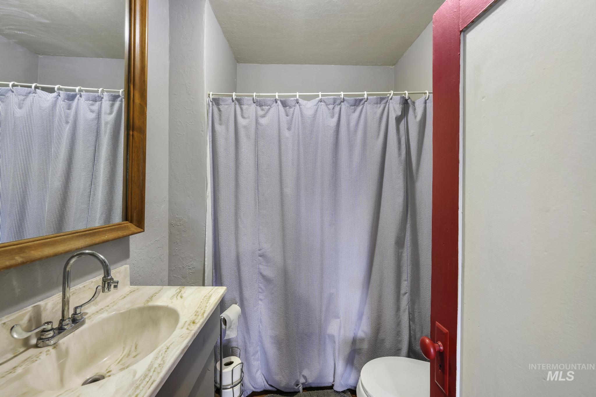 Full bathroom featuring vanity, a textured wall, and a shower with shower curtain