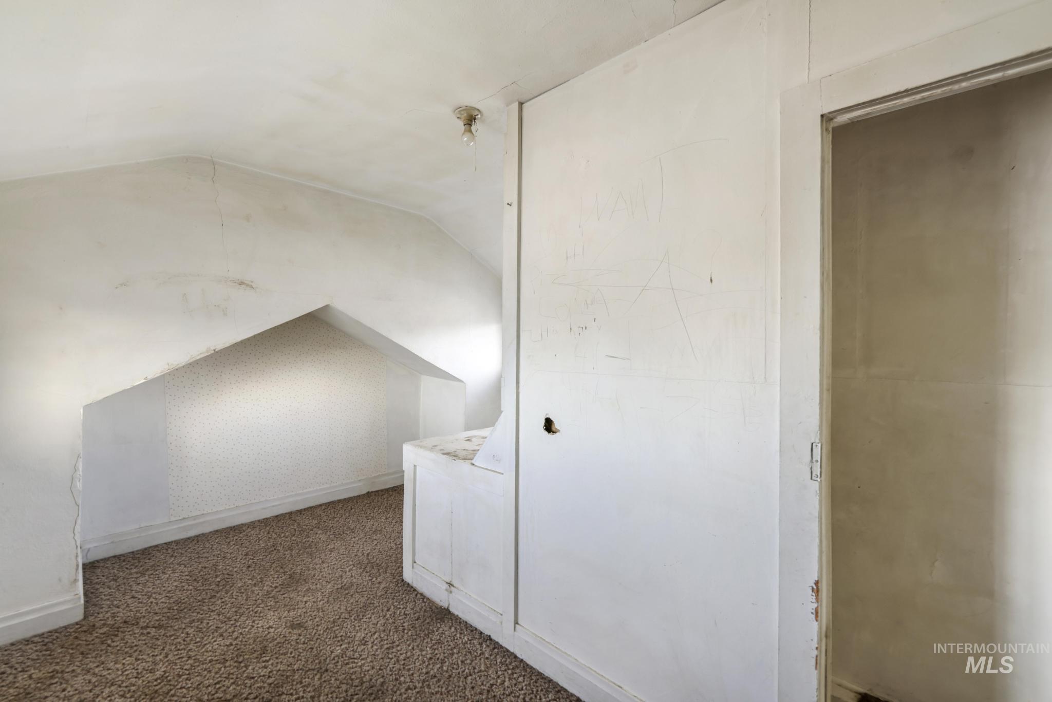 Bonus room with dark colored carpet and lofted ceiling