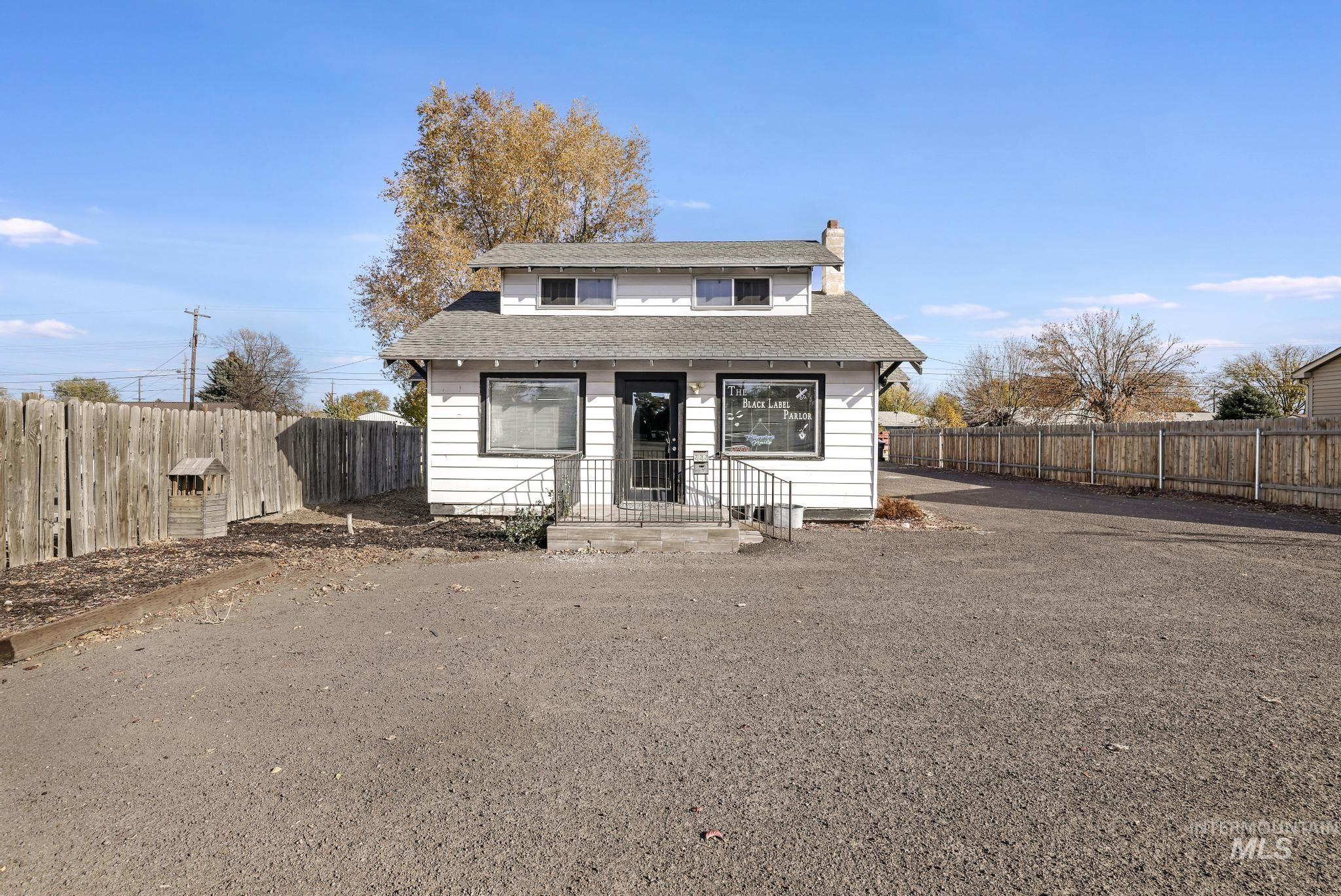 Bungalow-style home featuring a chimney, a fenced backyard, and a shingled roof