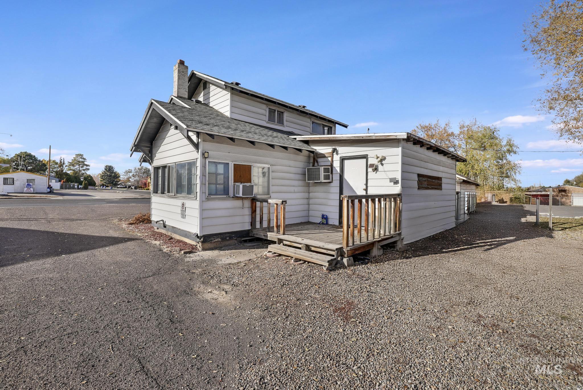 View of front of property with a wooden deck, roof with shingles, and a chimney