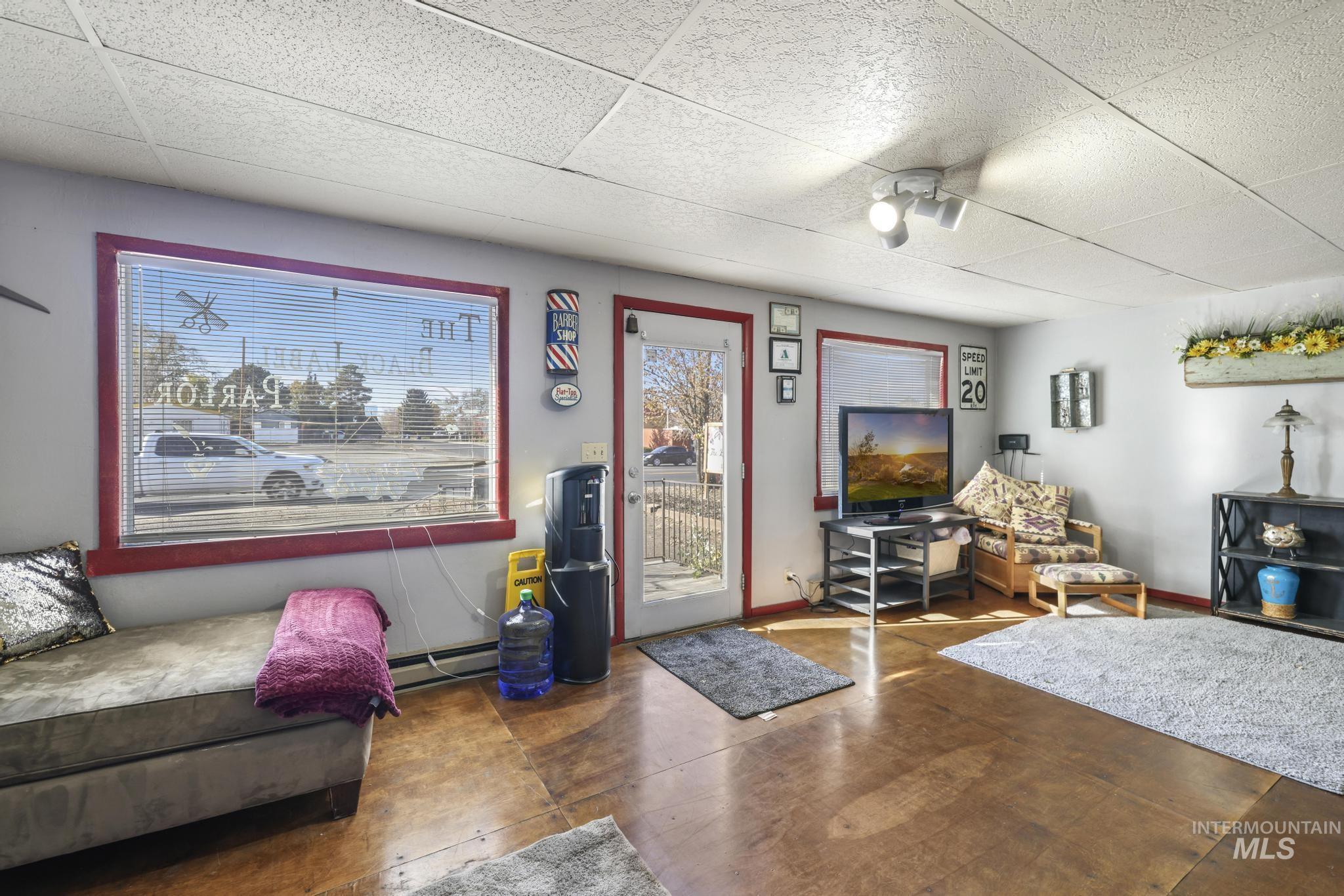 Living area with baseboard heating and a paneled ceiling