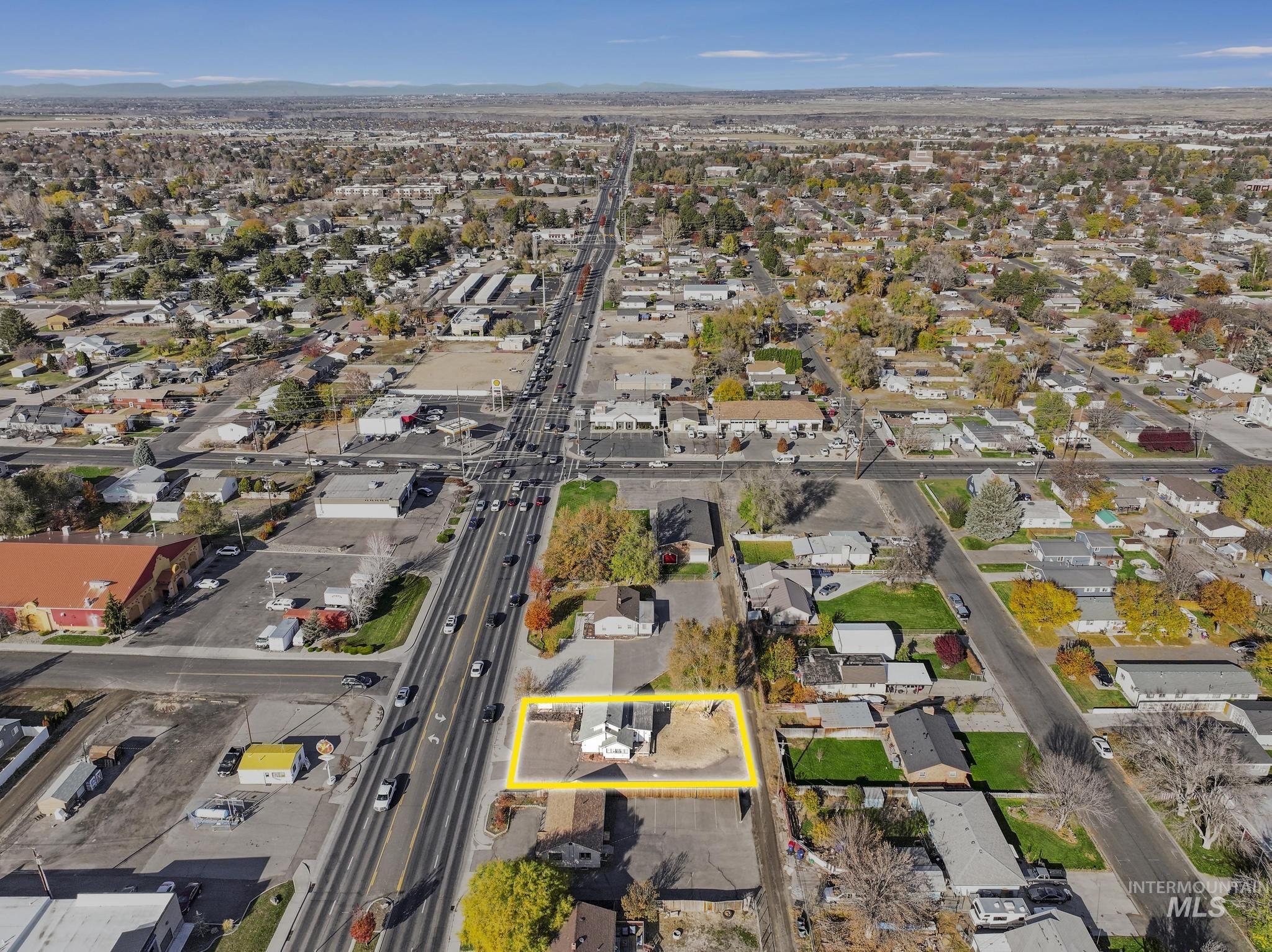 Aerial view of property and surrounding area featuring nearby suburban area and property parcel outlined