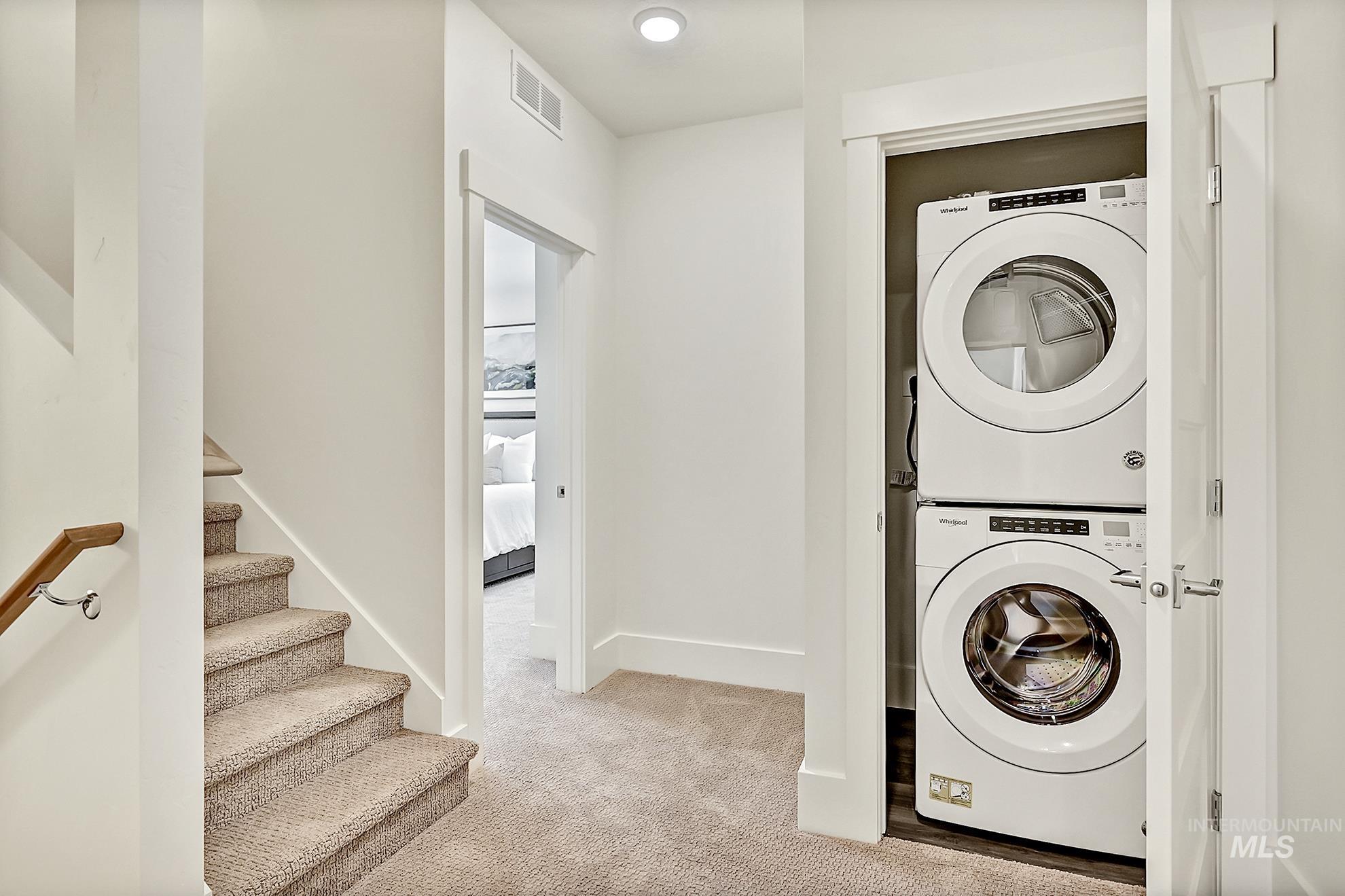 Laundry area with light carpet and stacked washer / dryer