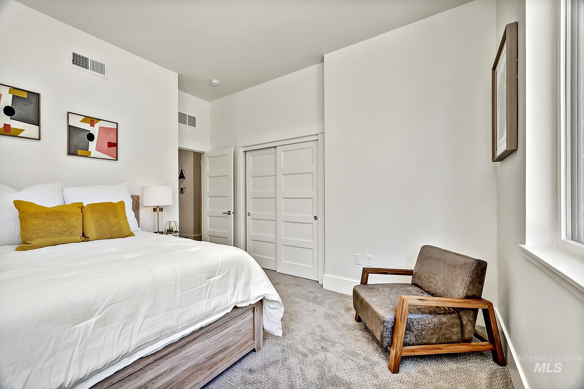 Bedroom with light colored carpet and a closet