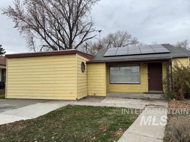 View of front of home featuring solar panels and a front yard
