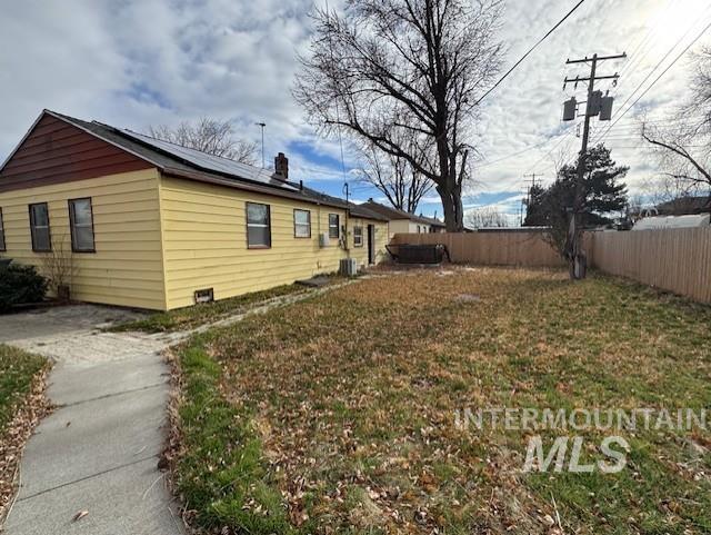 View of home's exterior featuring roof mounted solar panels, a chimney, and a fenced backyard