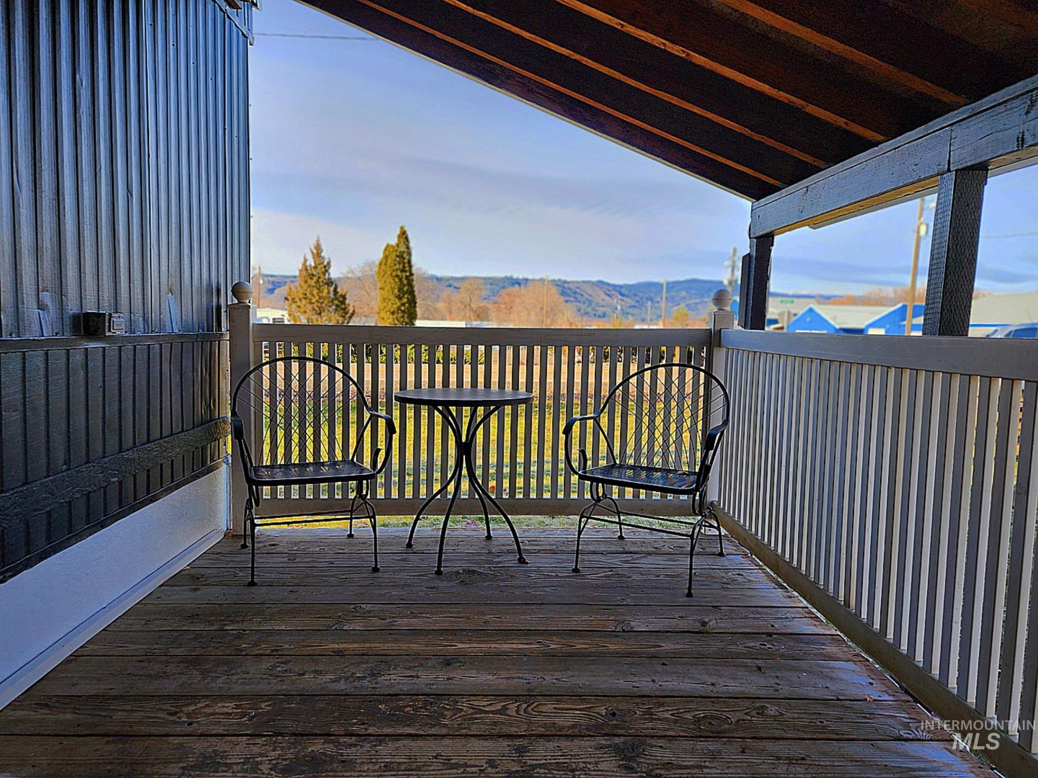 Covered porch with a peaceful view of rolling hills and open space. The wood decking and vaulted roof create a cozy spot for morning coffee or evening unwinding. A perfect outdoor retreat that extends your living space year-round.