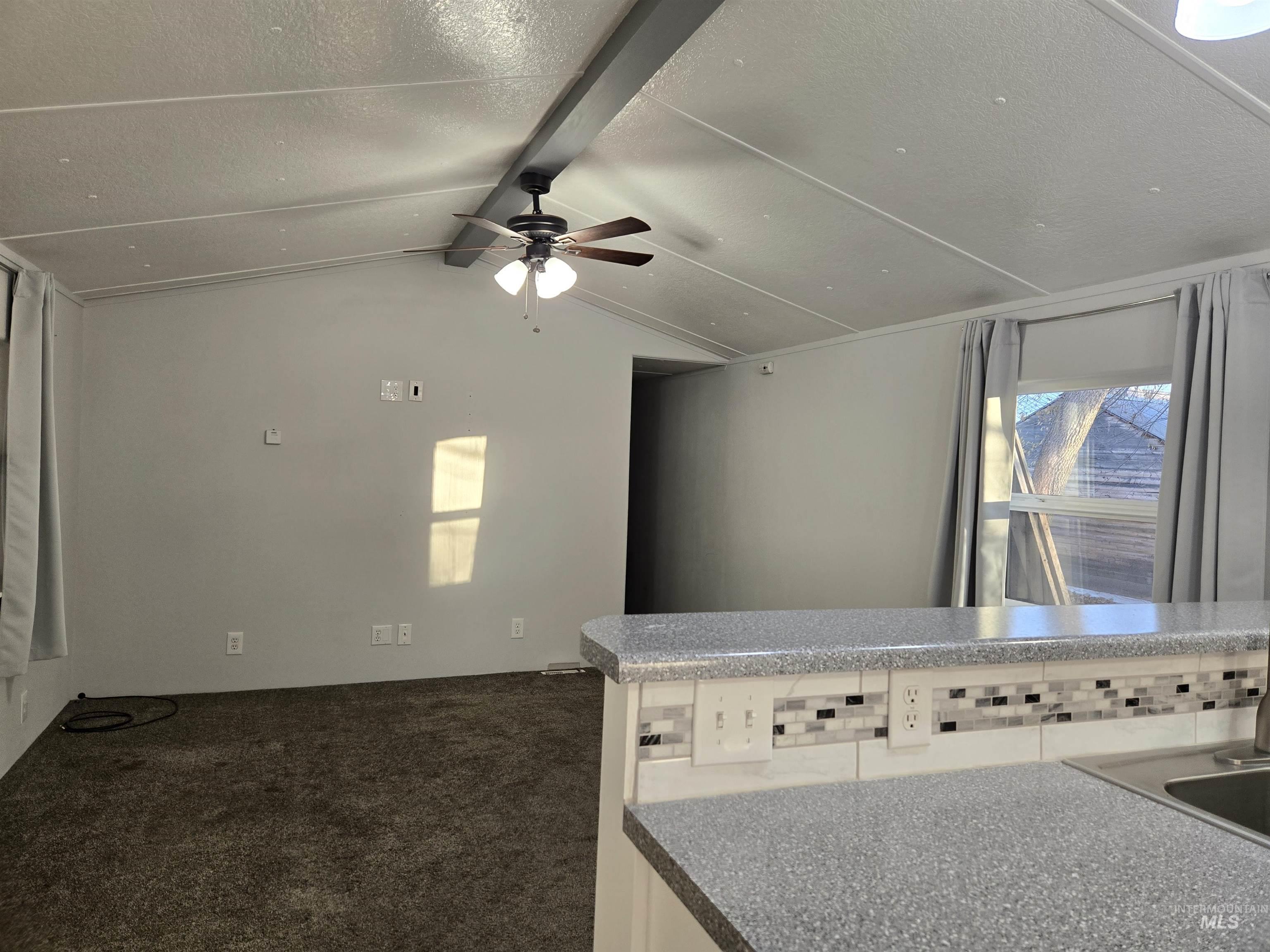 Open living room with fresh paint, vaulted ceiling, updated lighting, and great natural light. The spacious layout offers flexibility for seating and décor, creating a comfortable setting that flows easily from the kitchen.