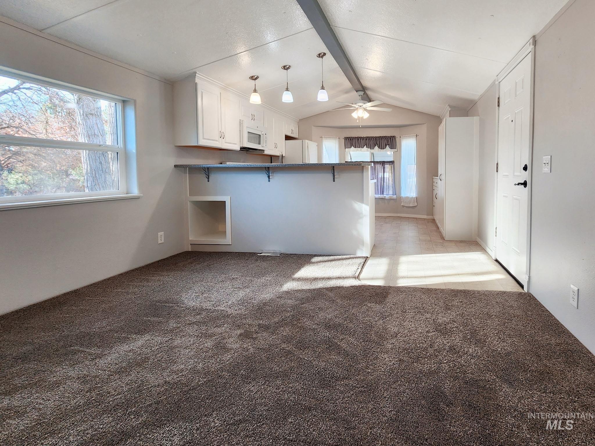 Spacious open-concept living area with new carpet, bright natural light, and a seamless flow to the kitchen. Updated lighting and neutral finishes make this space easy to furnish and instantly inviting.