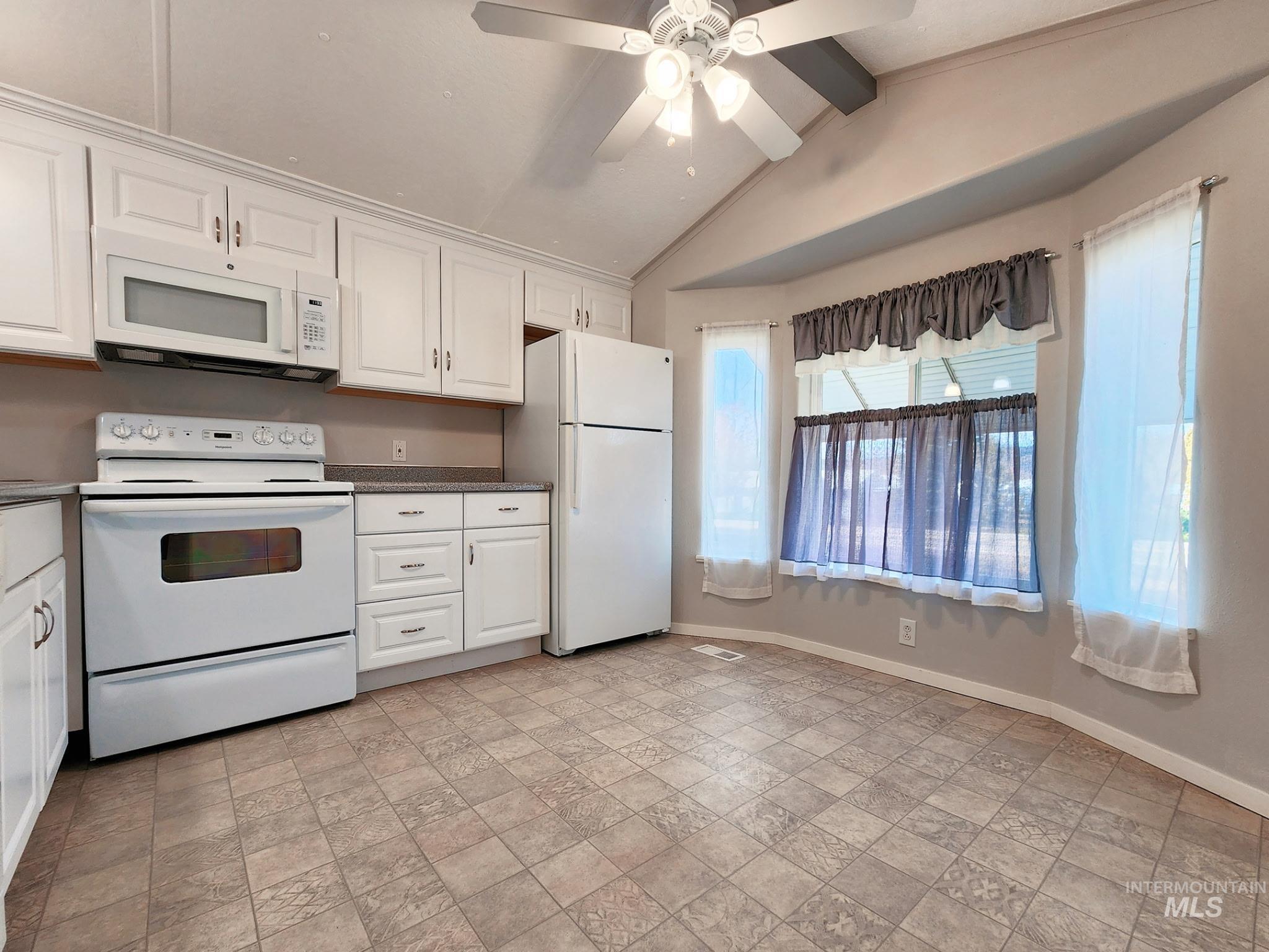 Bright kitchen with white cabinetry, clean appliances, and a spacious dining nook framed by large windows. Neutral finishes and ample storage create a welcoming, move-in-ready space perfect for everyday Idaho living.