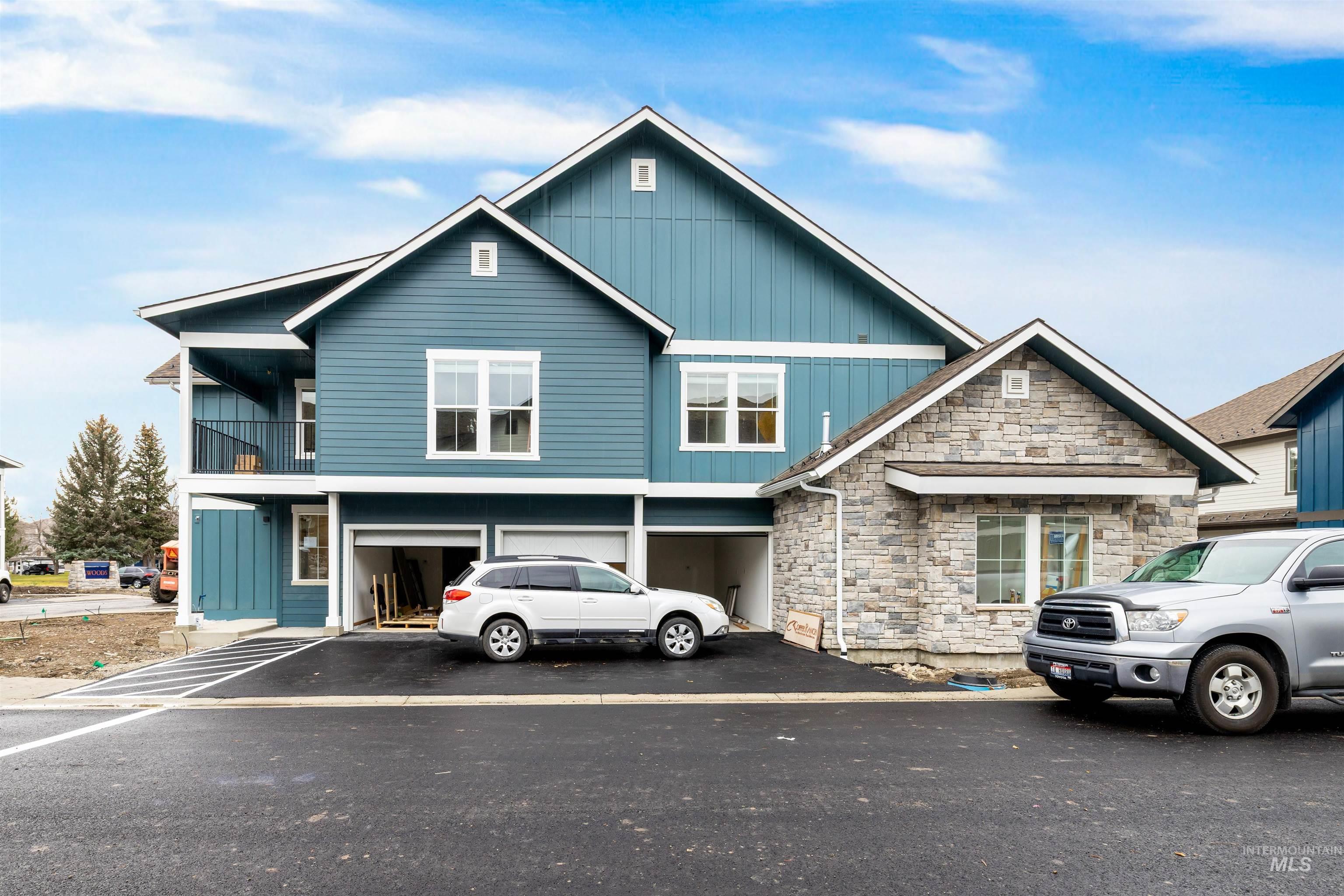 View of front of property with board and batten siding, stone siding, asphalt driveway, and a balcony