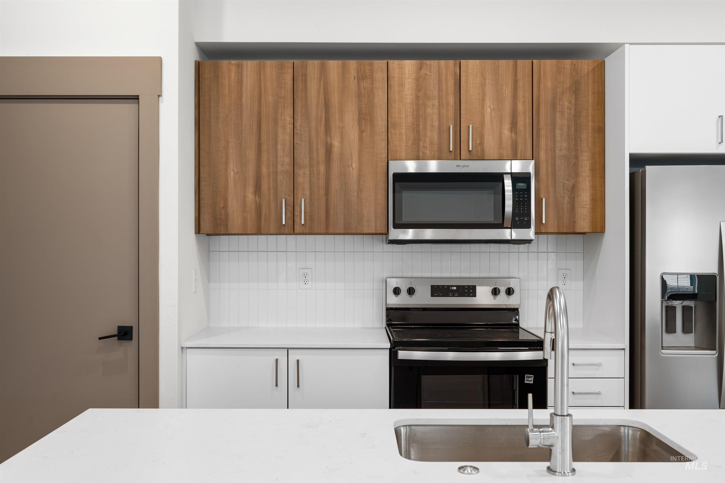 Kitchen featuring appliances with stainless steel finishes, brown cabinetry, tasteful backsplash, and modern cabinets