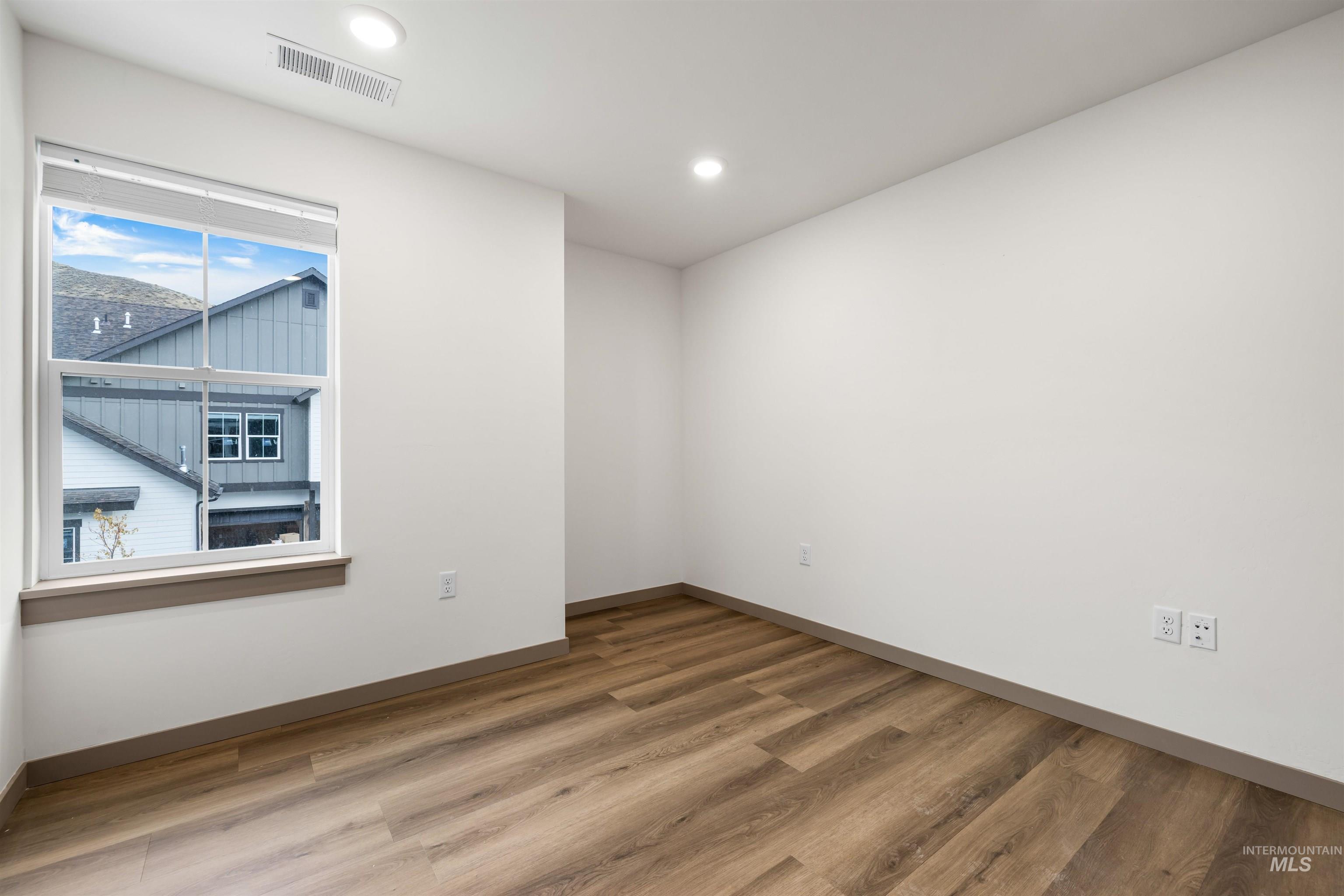 Unfurnished room with wood finished floors and recessed lighting