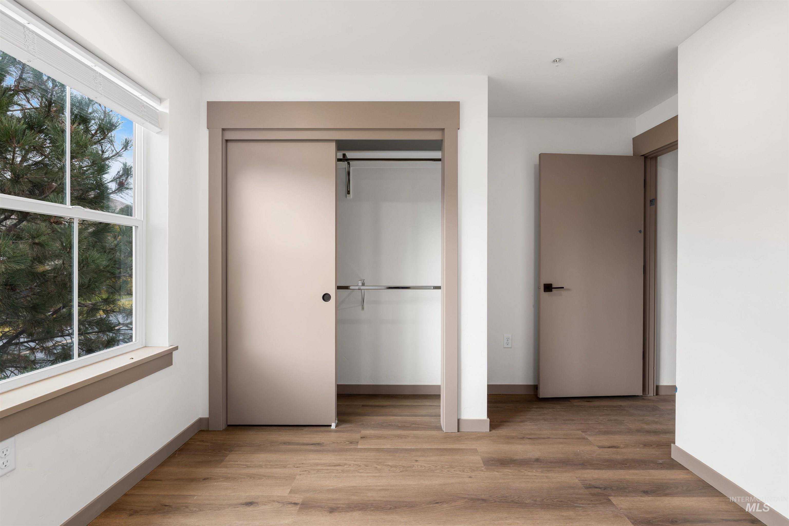 Unfurnished bedroom featuring light wood-style floors, a closet, and multiple windows