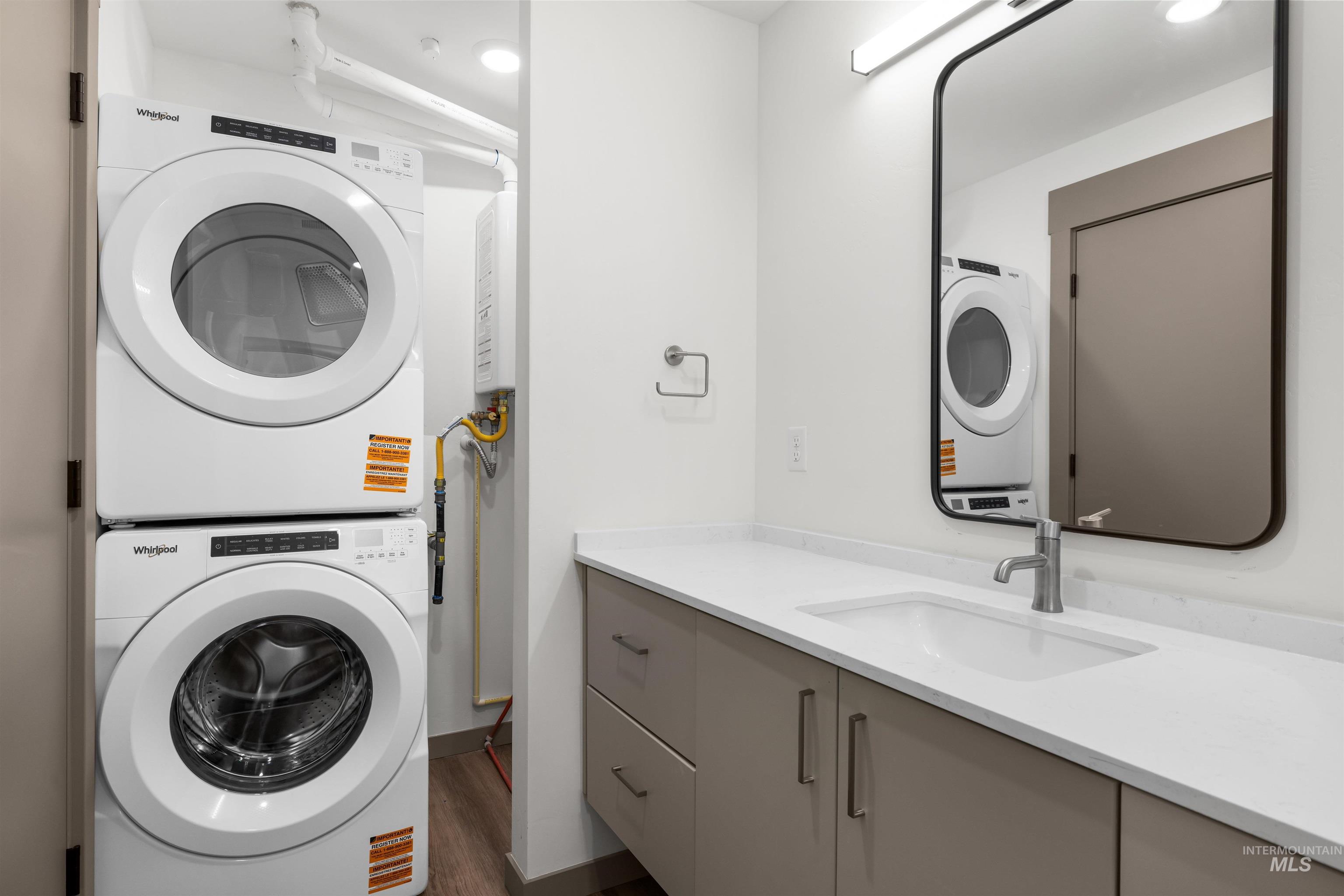 Laundry room with estacked washer and dryer, dark wood-type flooring, and recessed lighting
