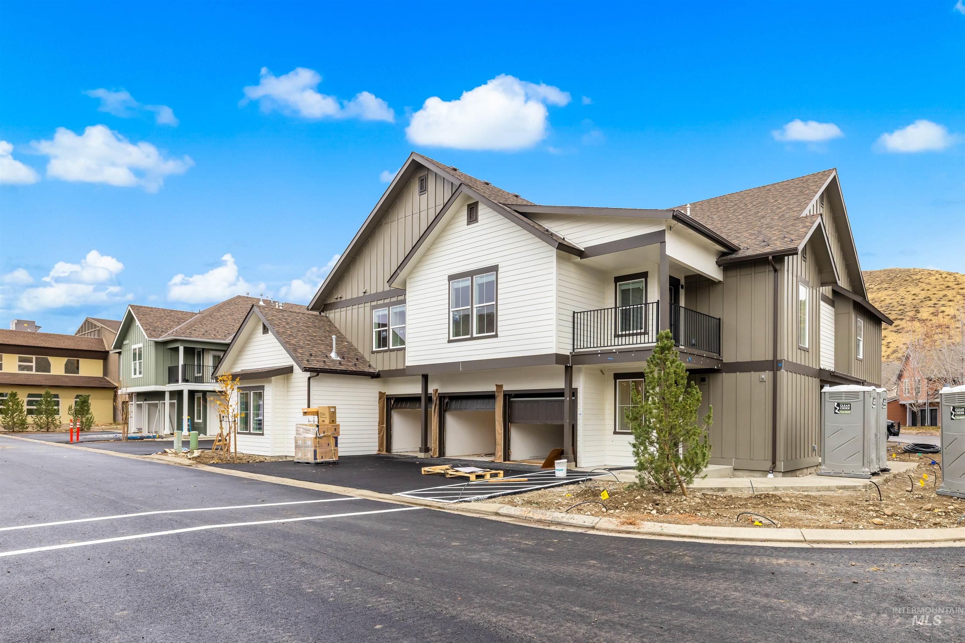 View of front facade with a garage, board and batten siding, roof with shingles, a residential view, and driveway