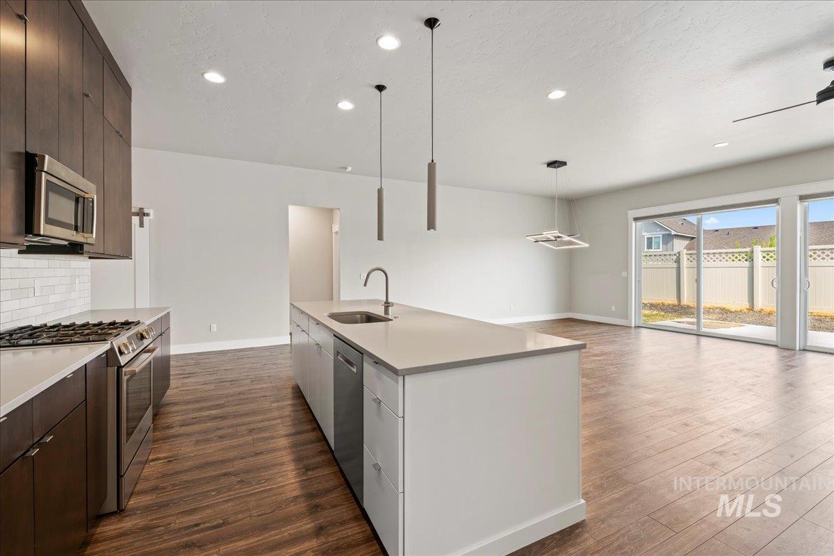 Kitchen with stainless steel appliances, dark wood finished floors, dark brown cabinetry, decorative backsplash, and modern cabinets