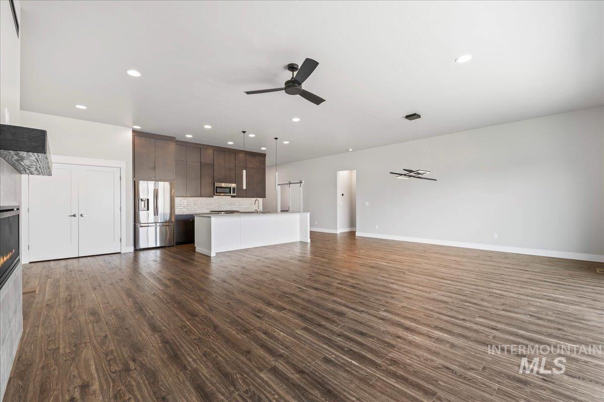 Unfurnished living room featuring ceiling fan, dark wood finished floors, recessed lighting, and a glass covered fireplace