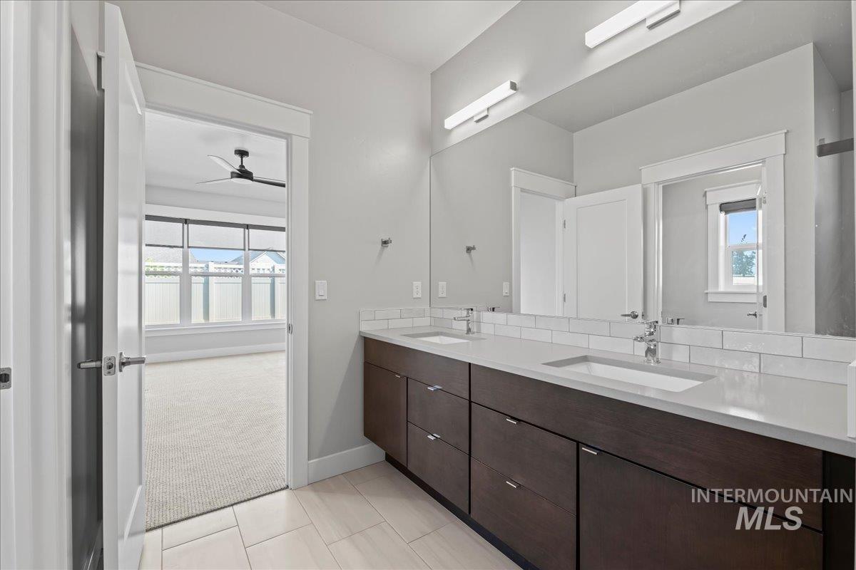 Full bathroom with double vanity, ceiling fan, and tile patterned flooring