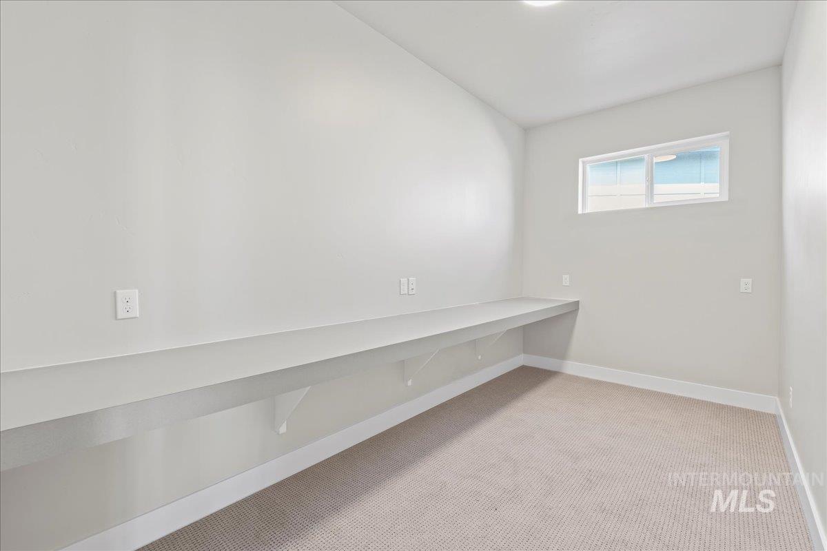 Unfurnished room featuring light carpet and baseboards