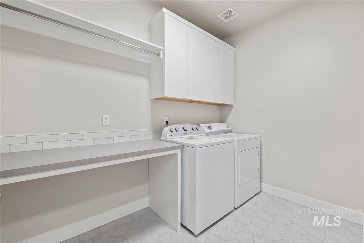 Washroom featuring cabinet space, washer and clothes dryer, and light tile patterned floors