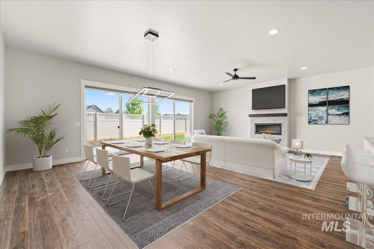 Dining room with a glass covered fireplace, wood finished floors, a ceiling fan, and recessed lighting