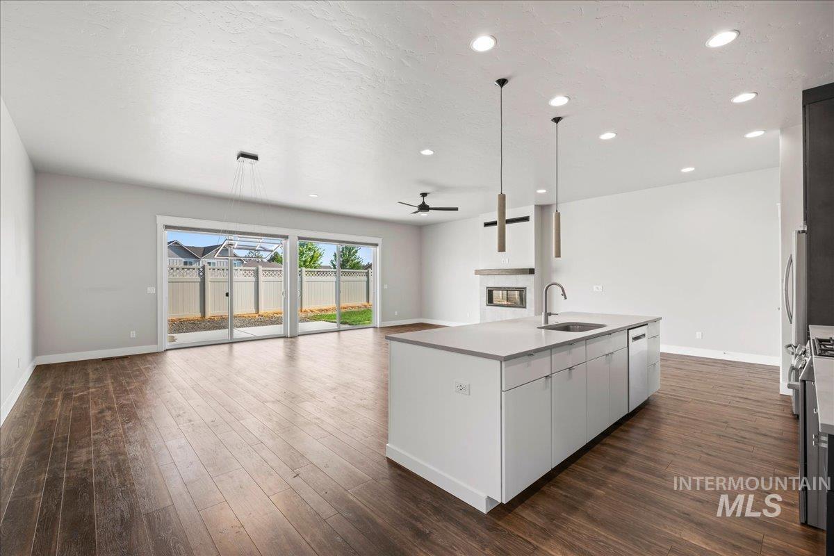 Kitchen featuring a glass covered fireplace, open floor plan, recessed lighting, dark wood-type flooring, and ceiling fan