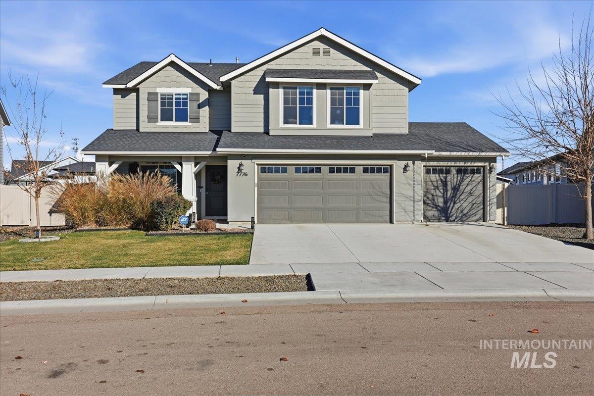 Craftsman-style house featuring roof with shingles, driveway, and a garage